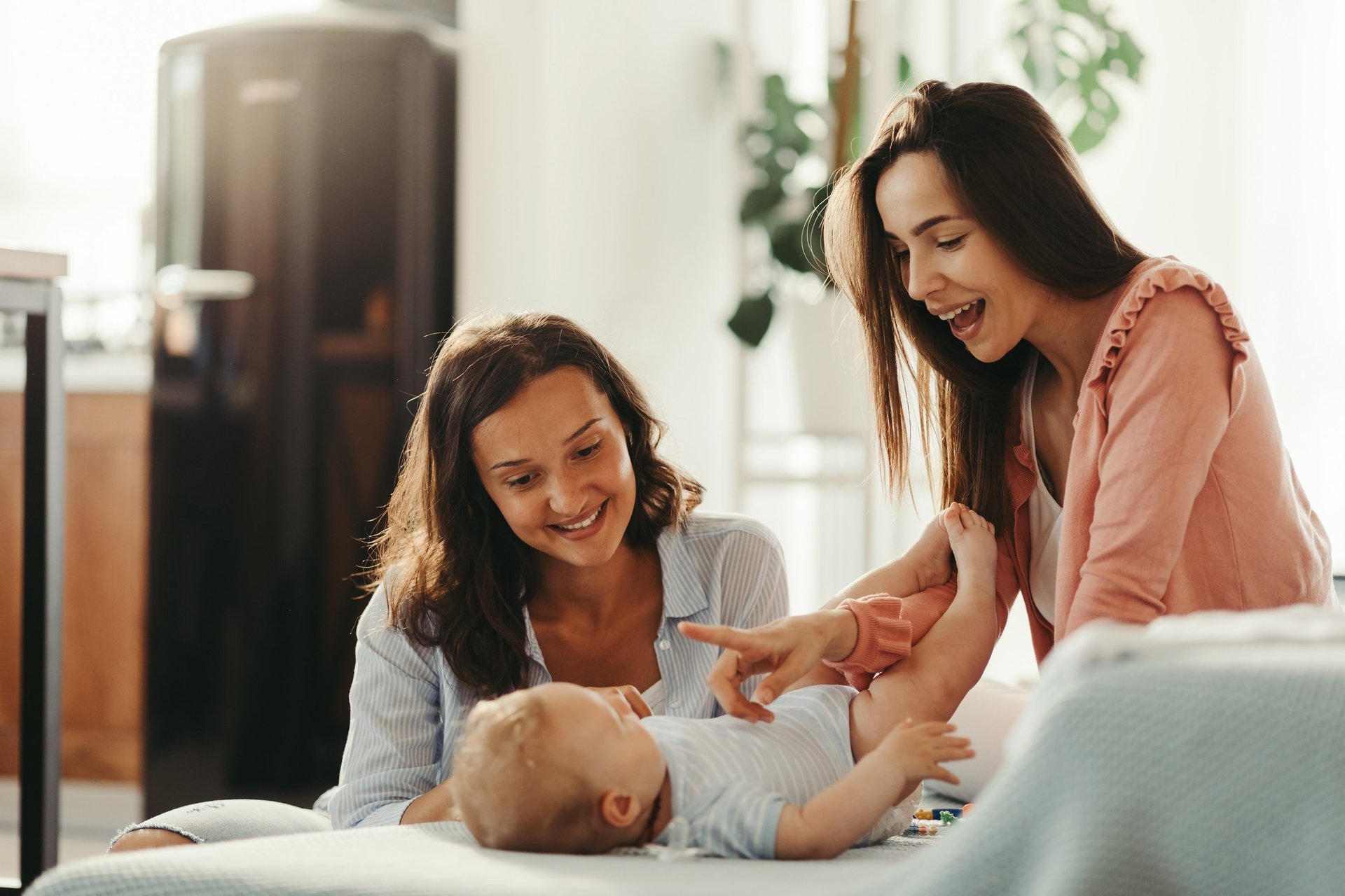 woman carrying baby with two ladies beside her smiling