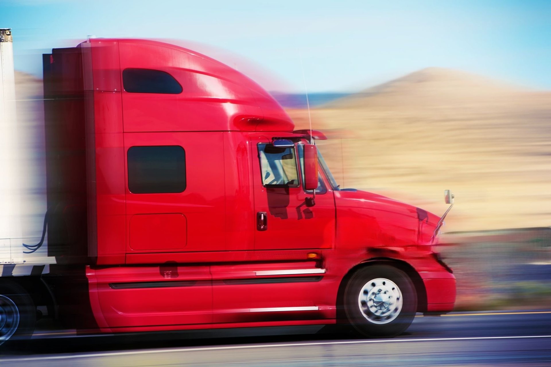 a red semi truck driving down a street