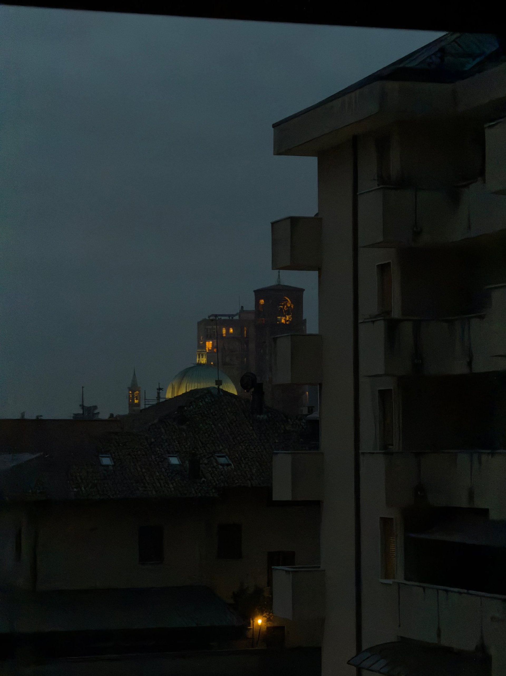 Modern skyscrapers illuminated at dusk with cloudy sky.