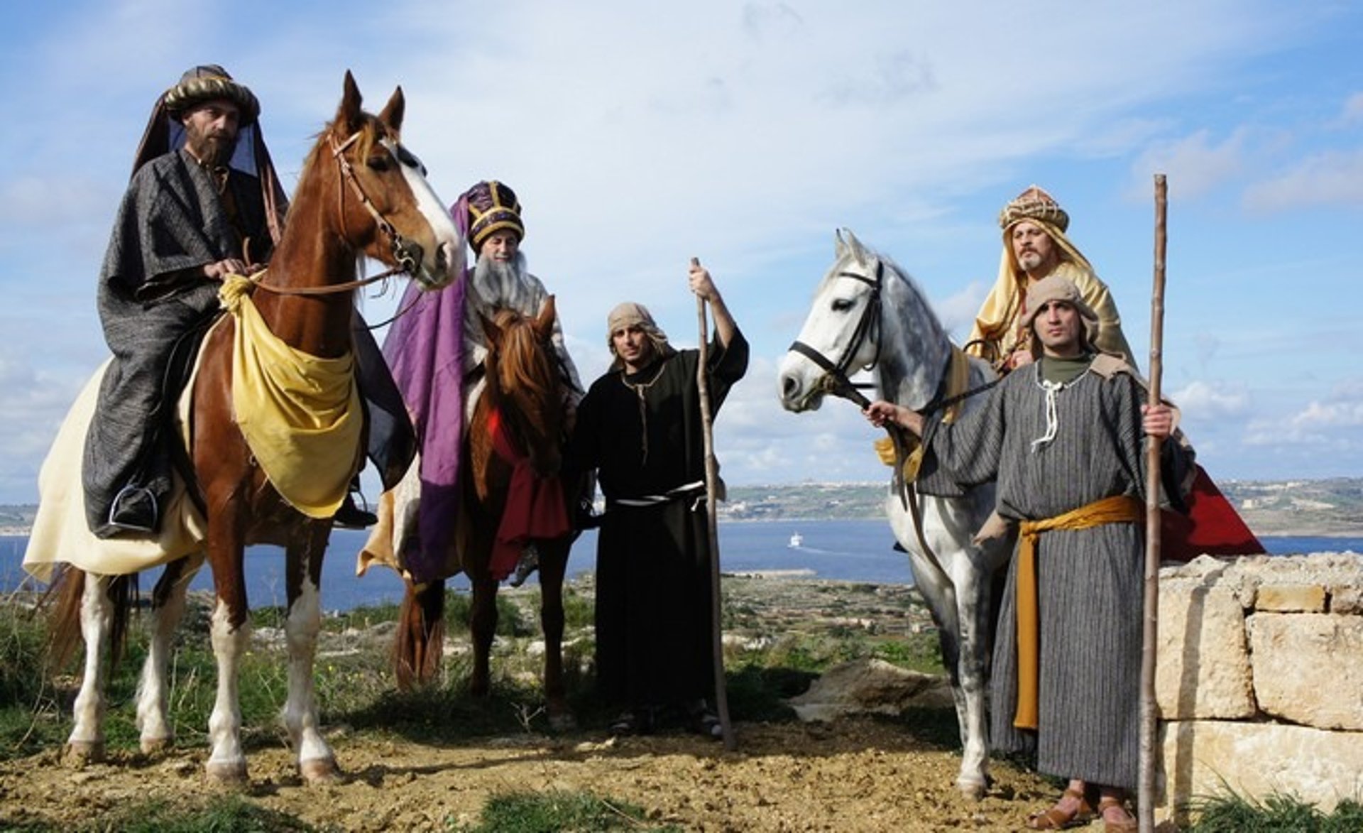 Three men dressed as the Wise Men, or Magi, from the New Testatment, sit on horseback, Two shepherds are holding the reigns.