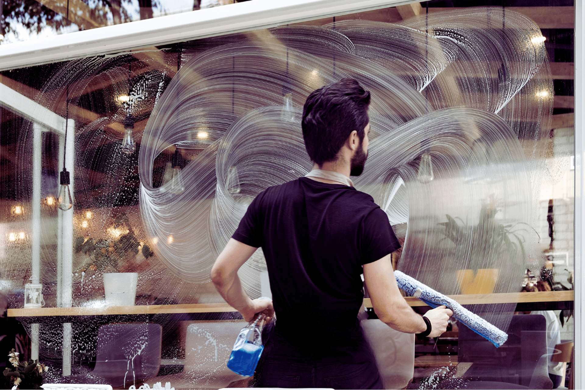 utility man standing in scissor platform cleaning glass window