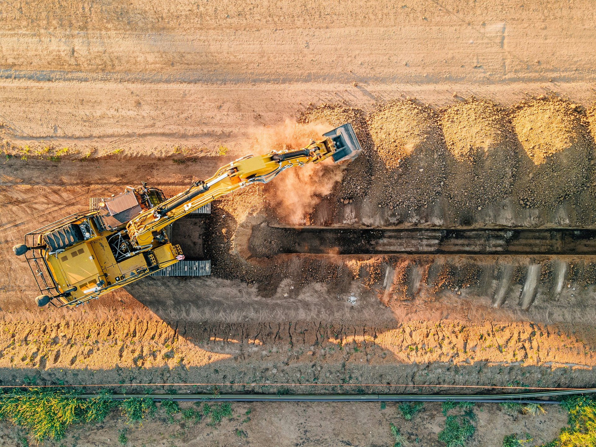a construction site with a large orange excavator and a small red truck