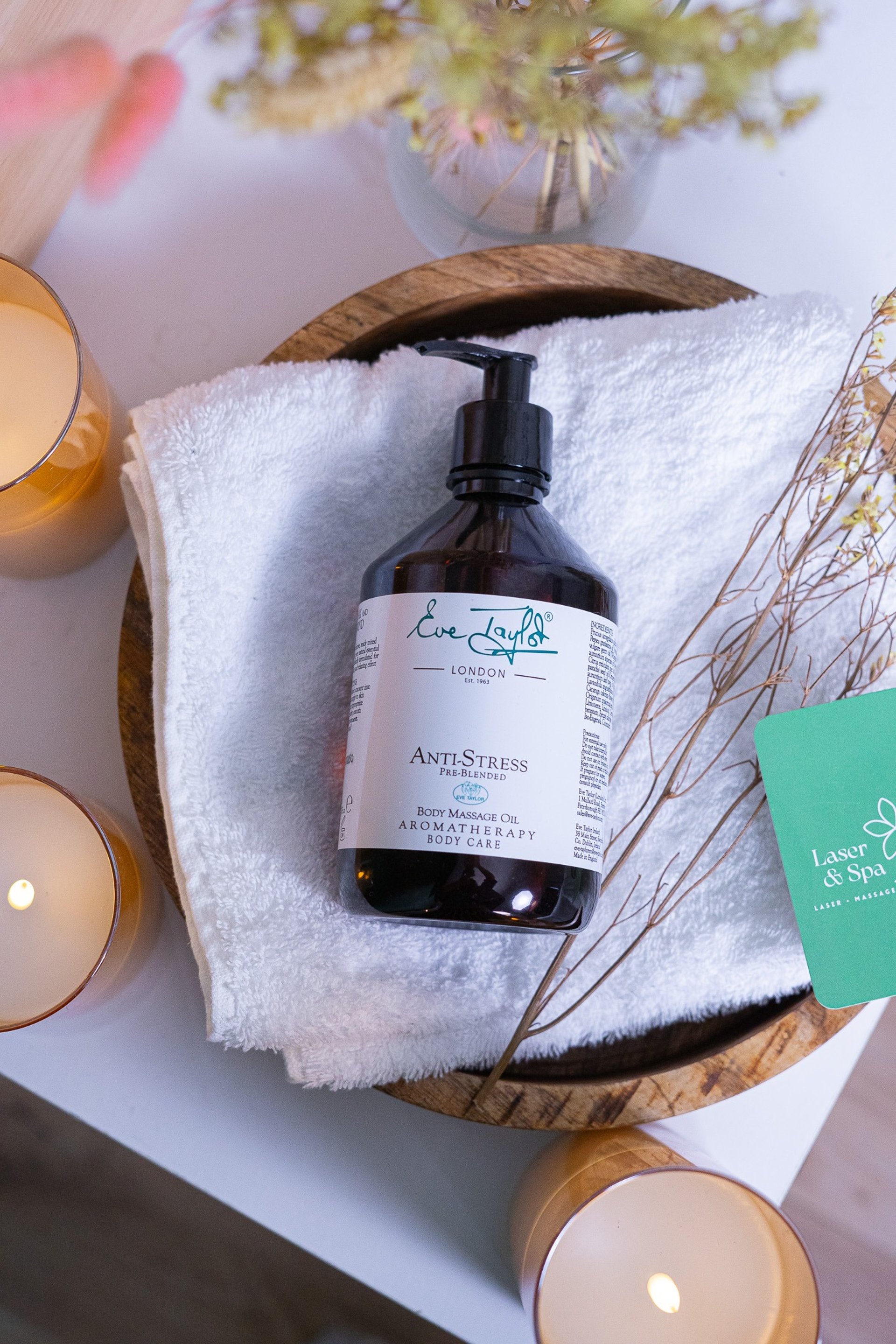 white plastic pump bottle beside pink tulips and gray towel