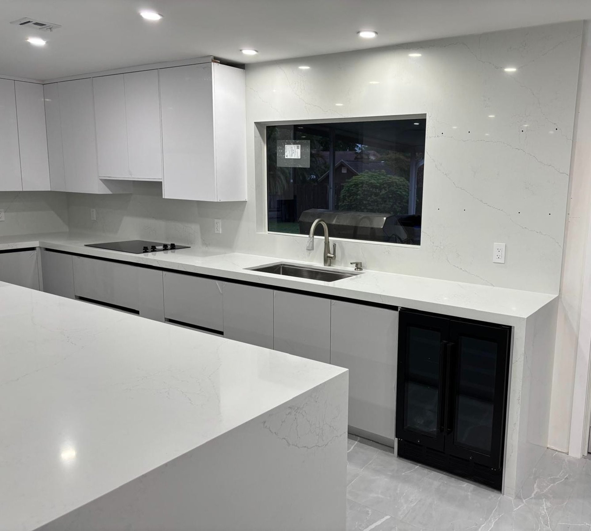 a kitchen with white cabinets and marble counter tops