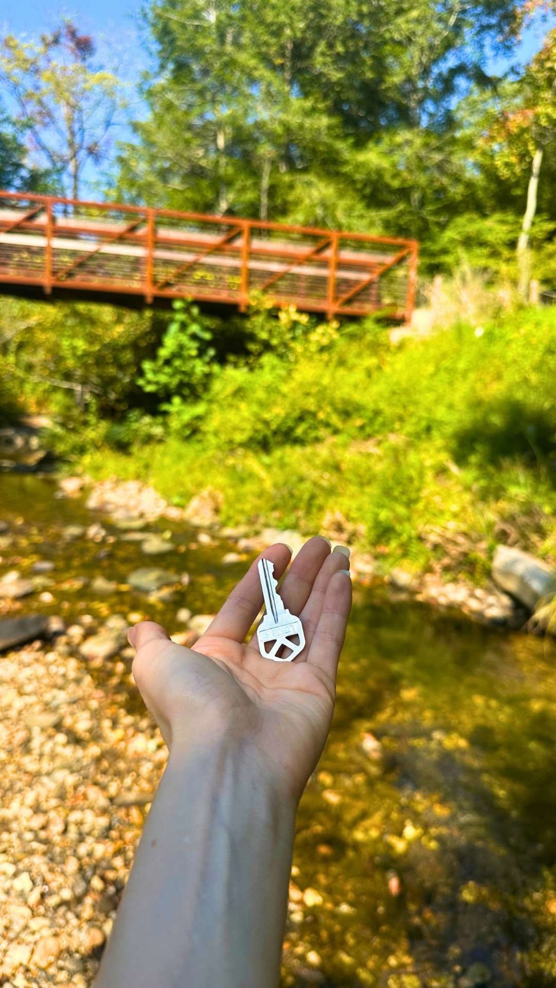 Hand holding a house key over a creek in Asheville, North Carolina