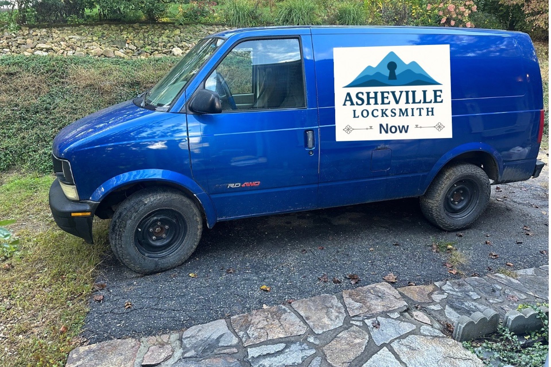 Blue work van with Asheville Locksmith logo driving through West Asheville