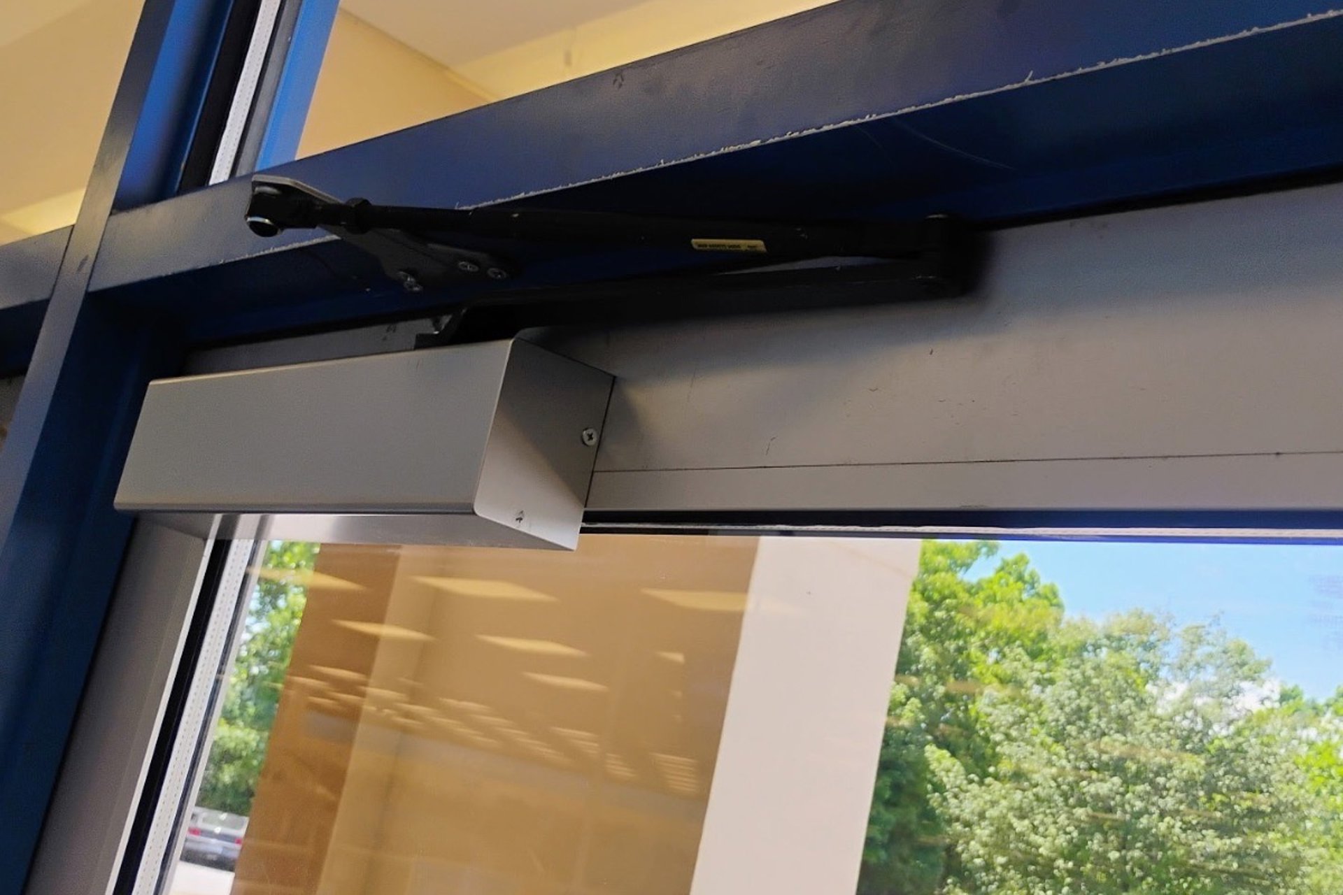 Commercial door closer installed on a glass storefront door at Tanger Outlets of Asheville, NC
