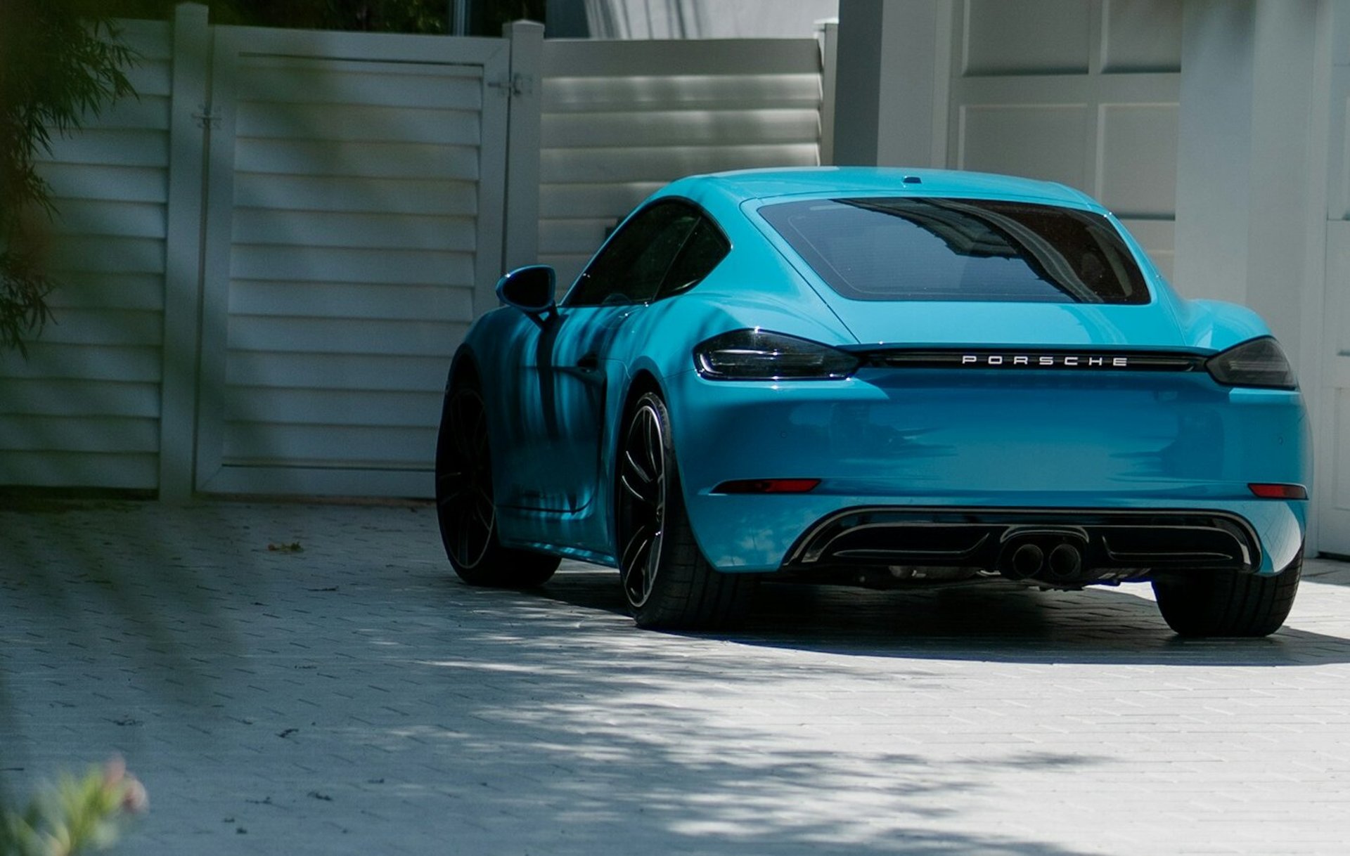 A blue porsche parked in front of a house.
