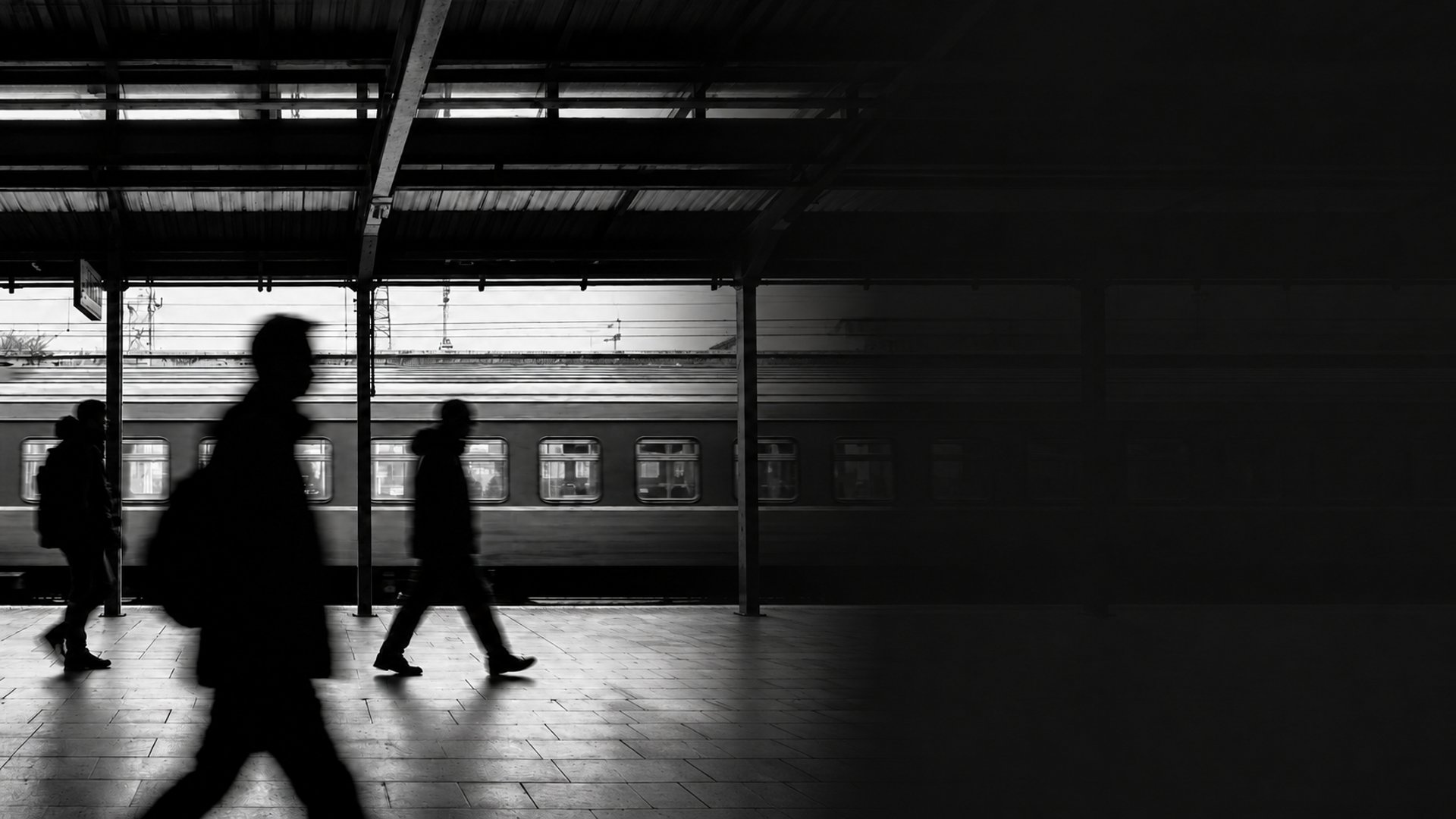 grayscale photo of person standing on train station