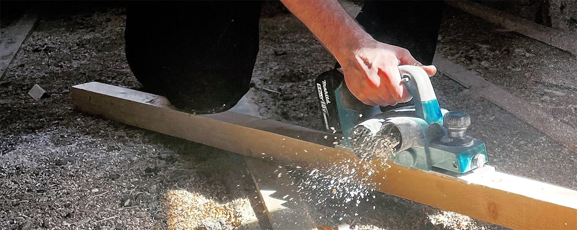 person in black leather jacket holding brown and black hiking shoes