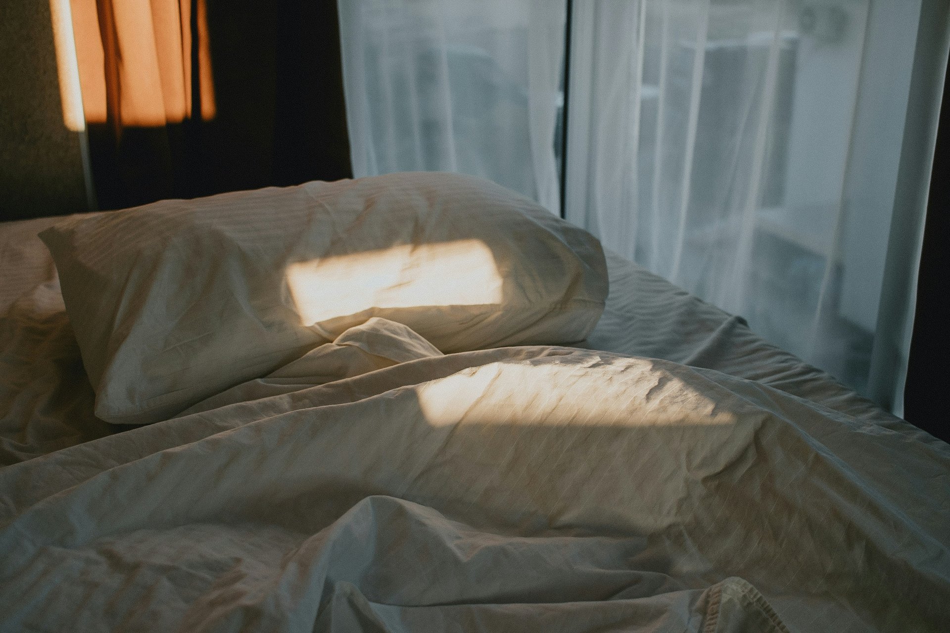 an unmade bed with a wooden head board