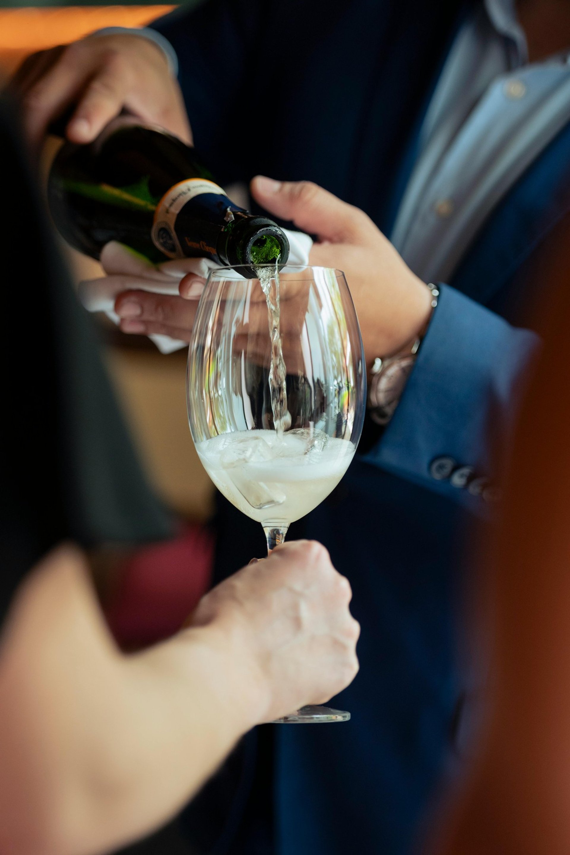 green glass bottle beside clear wine glass on white table
