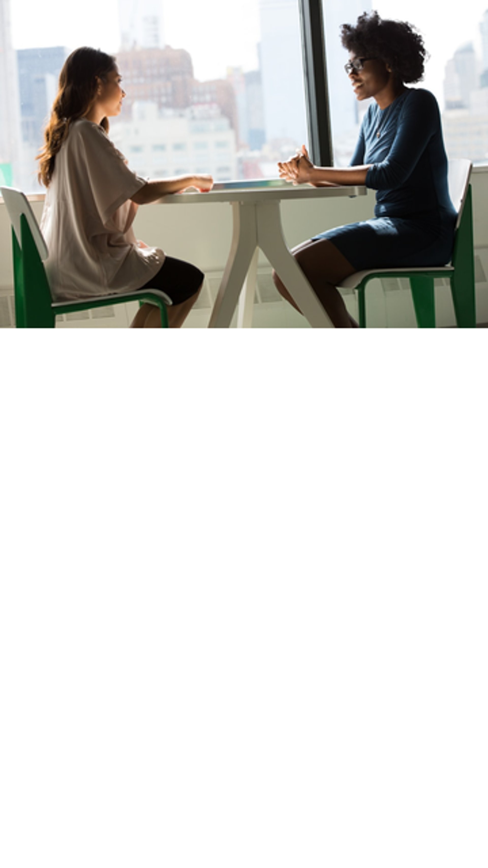 two women sitting beside table and talking