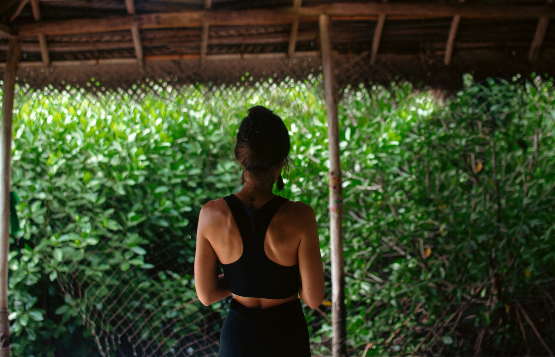 Isabel Maass, Psychologist (M.Sc.) and yoga teacher, seen from behind facing lush green, symbolizing mindfulness and presence