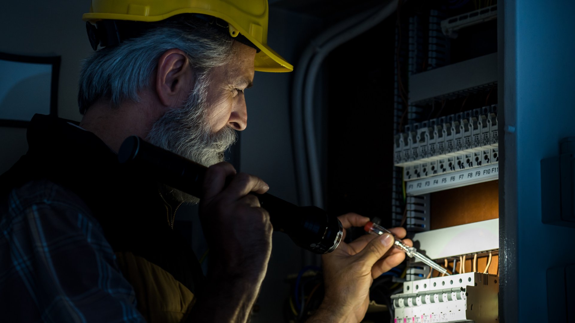 Man repairing a computer server under a lamp.