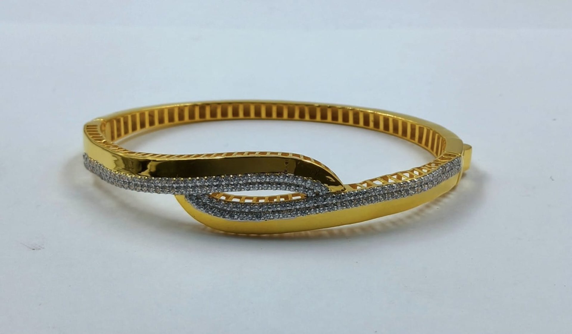 a pair of gold bracelets sitting on top of a wooden box