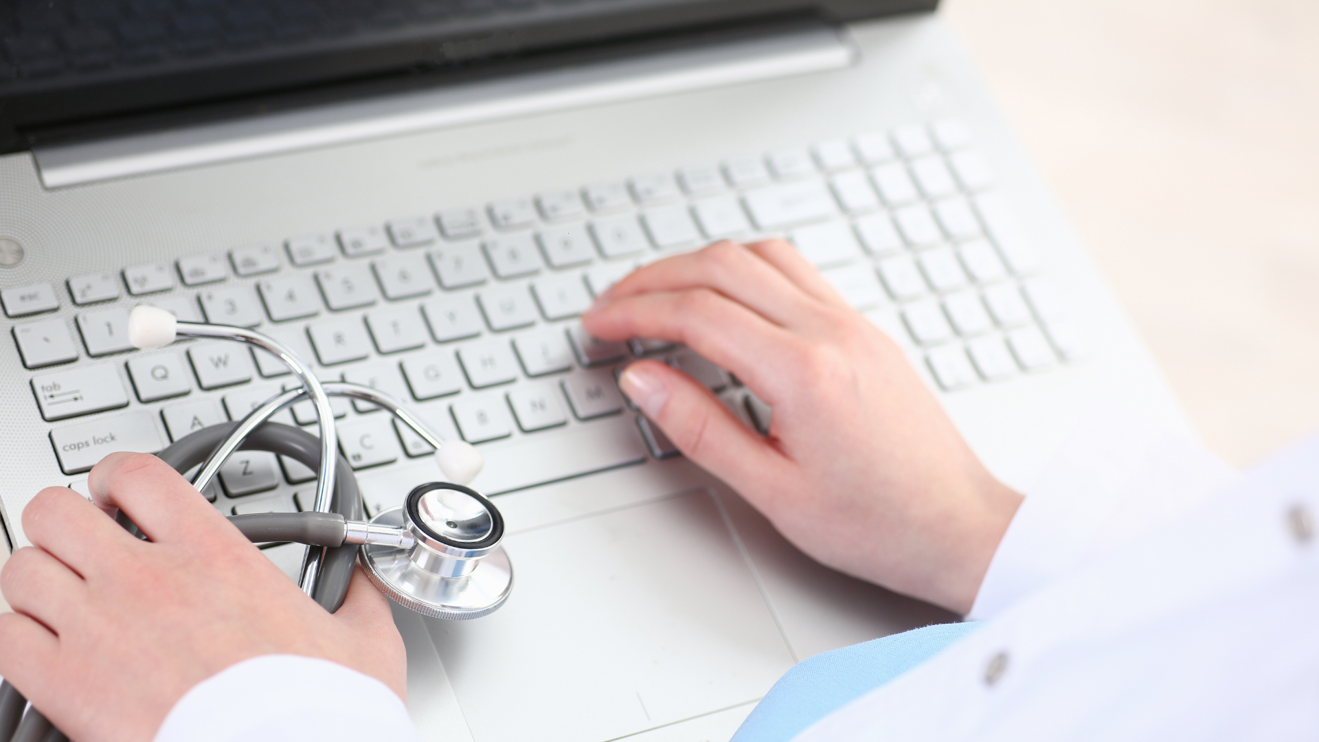 person holding pencil near laptop computer
