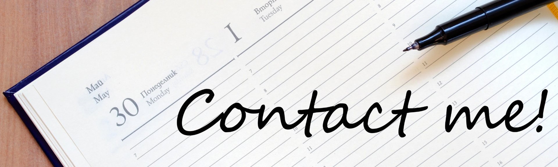 Picture of a desk diary with a pen resting on it and the words Contact Me written on the diary in large black handwriting.