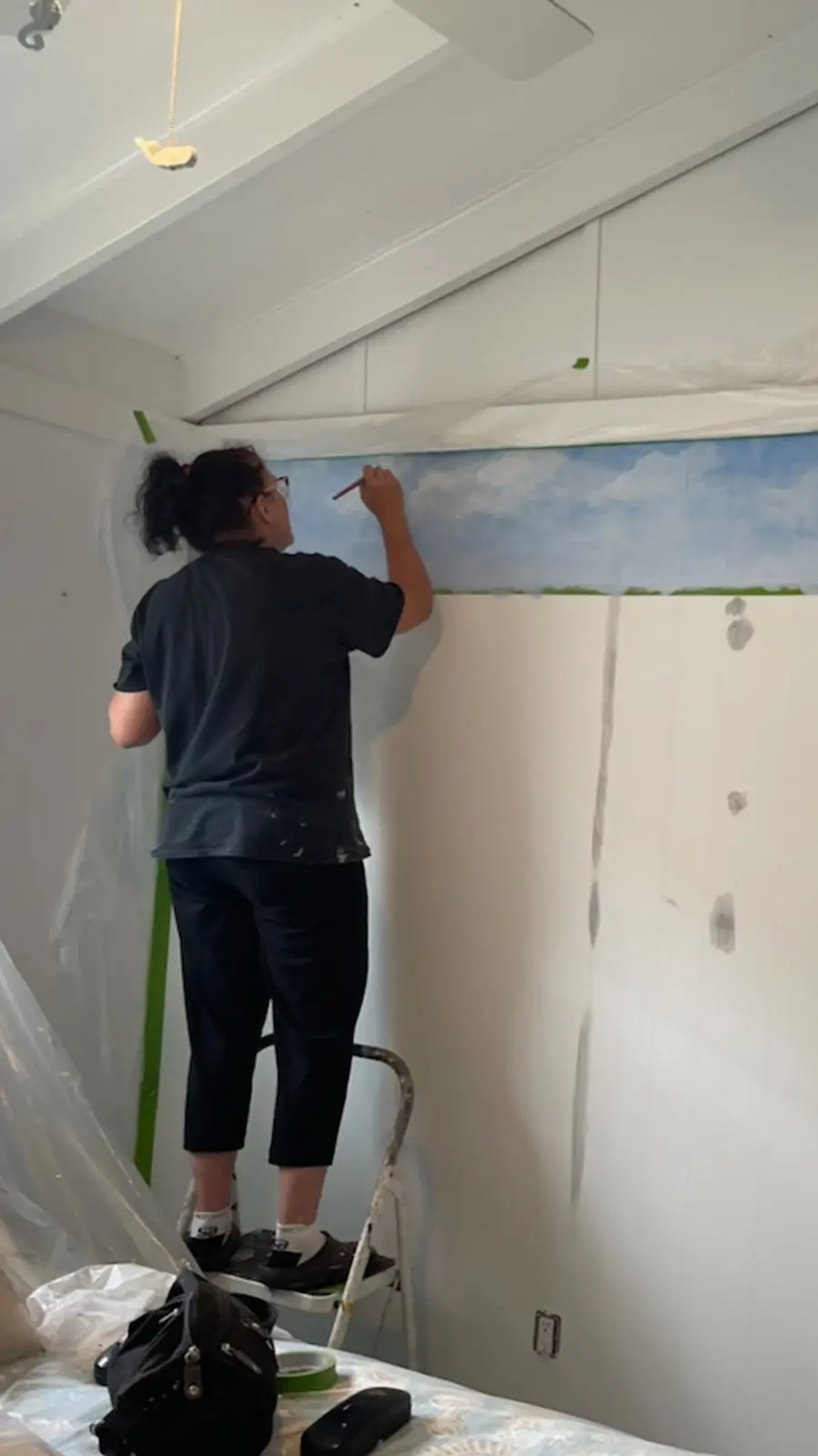 marcine on a ladder painting a bespoke mural in lavalette nj