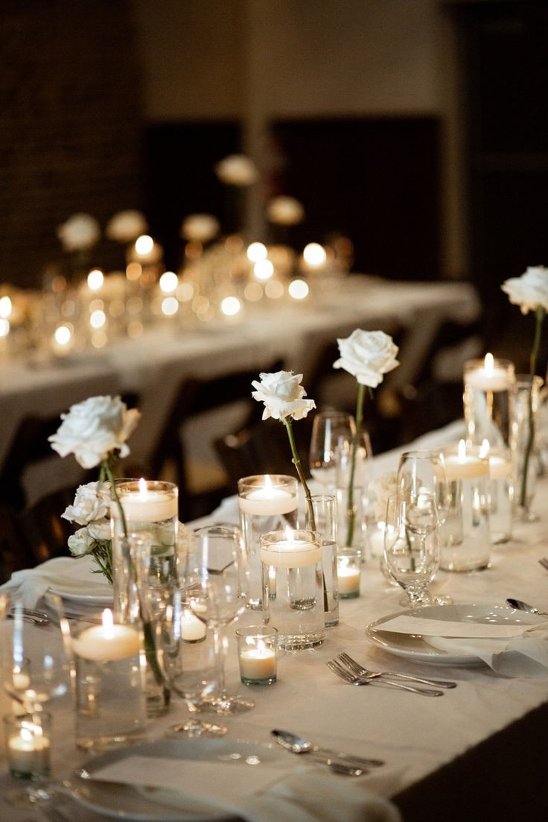 Mesas para evento decorada con manteles, llena de platos, tenedores, y otra decoracion