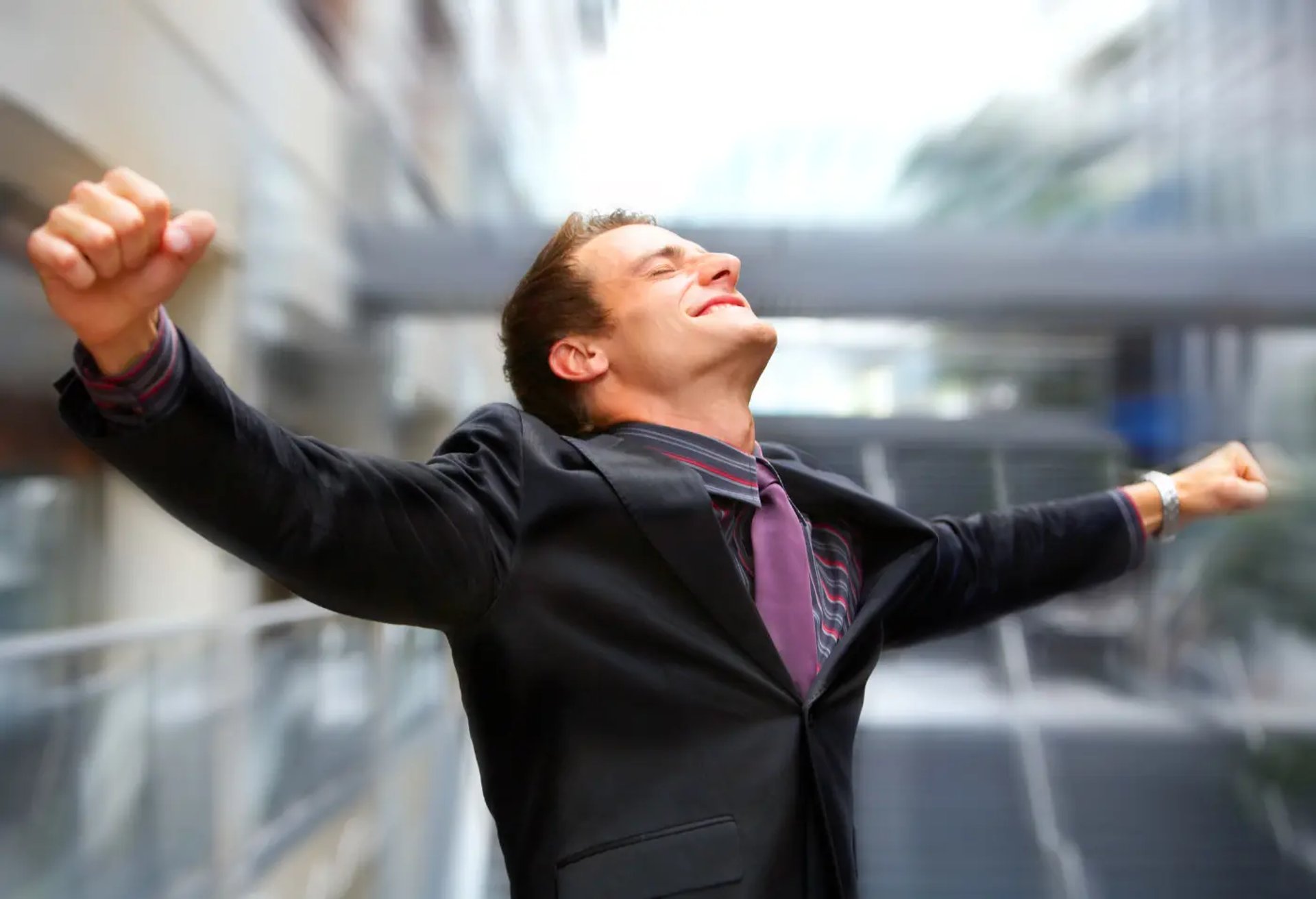 En överlycklig affärsman håller ut sina händer av lycka.