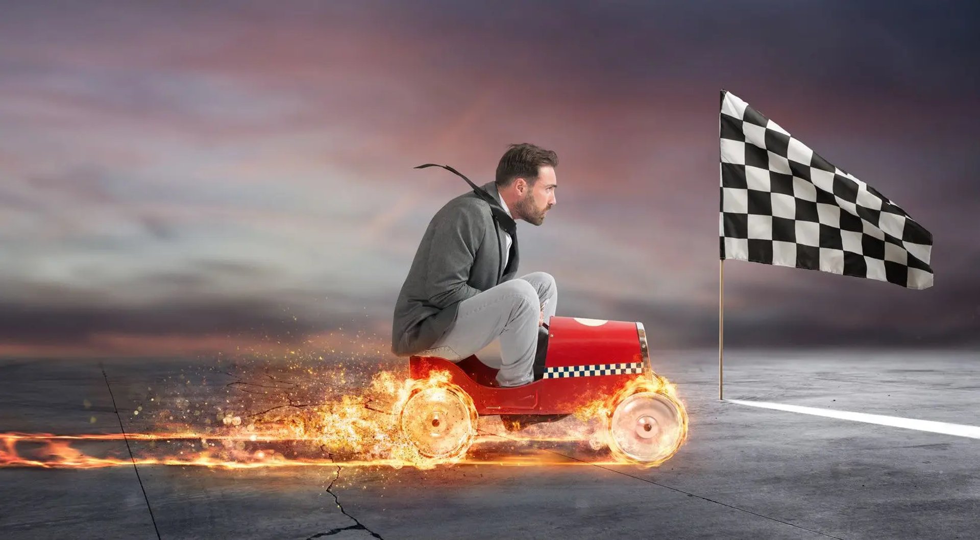 En affärsman kör en leksaksbil med brinnande hjul mot målgången.