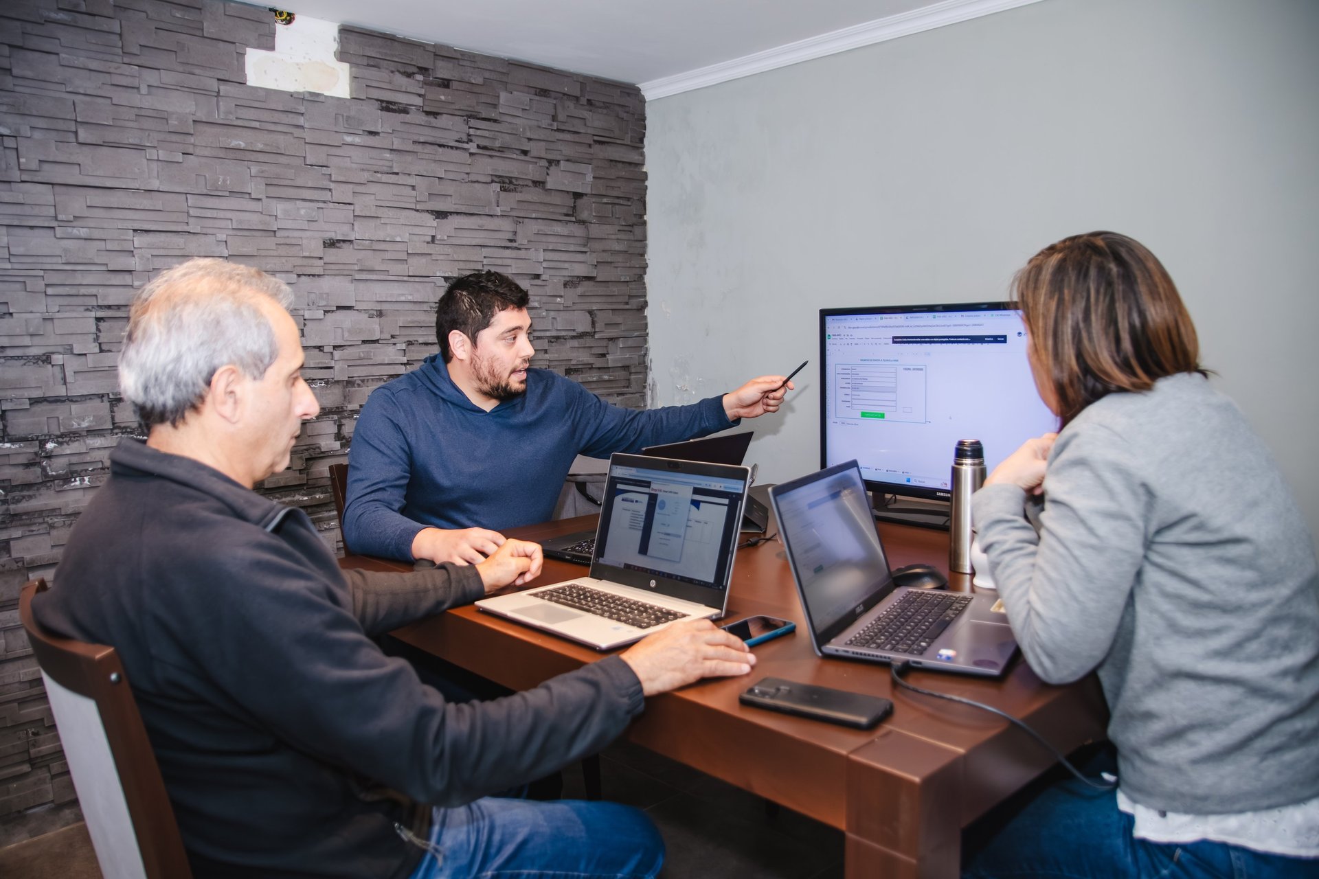 person holding pencil near laptop computer