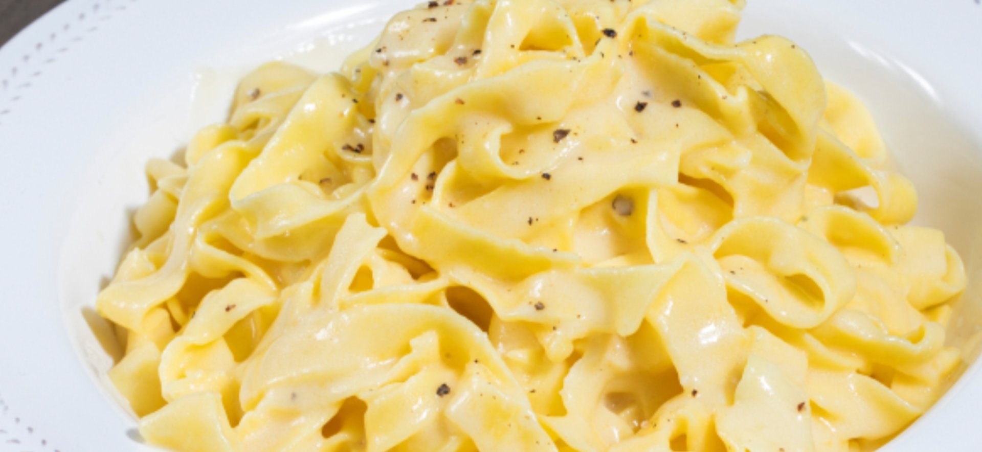 A white plate topped with pasta and bacon