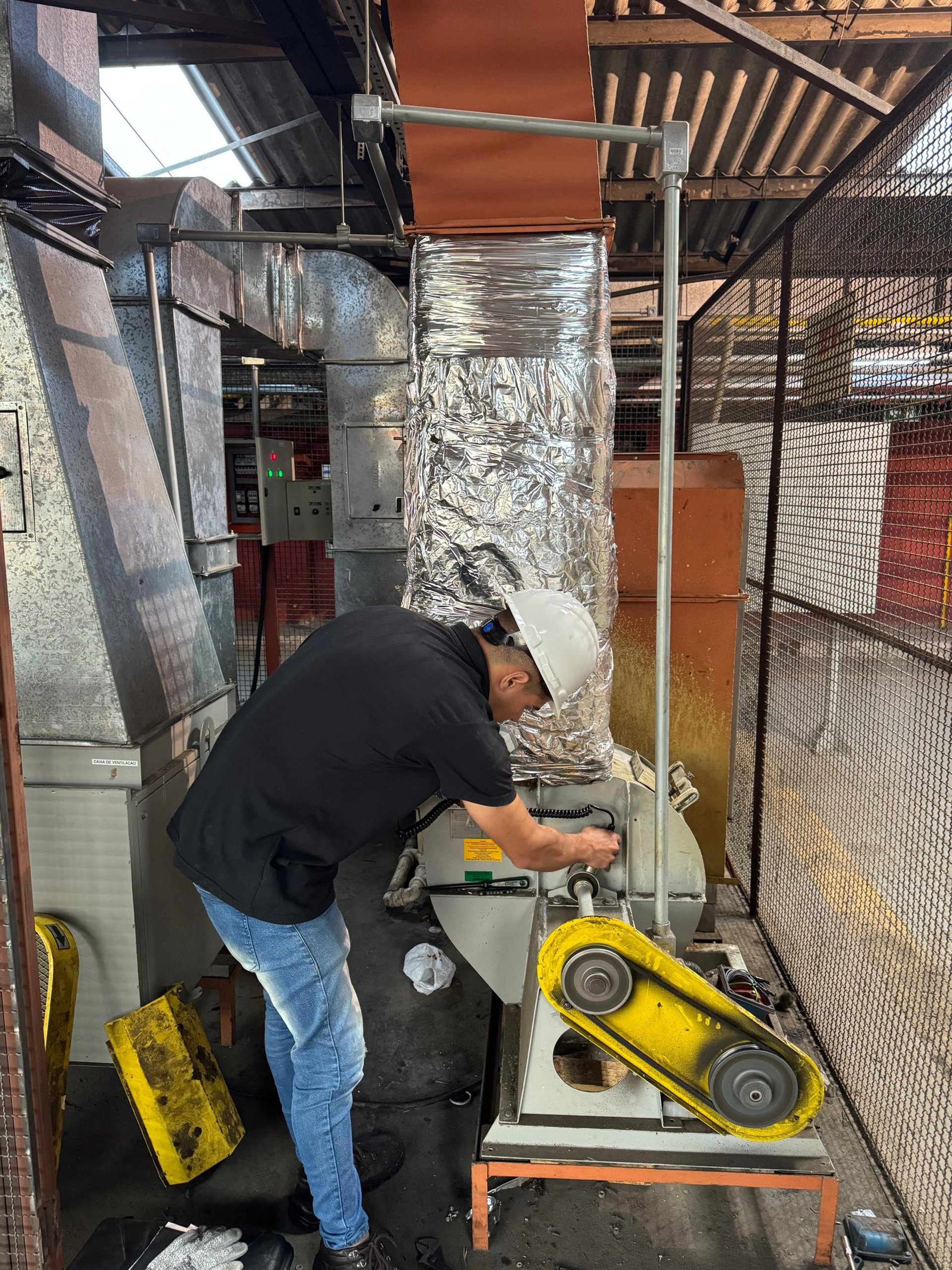 man in brown and white plaid dress shirt and yellow hard hat holding black and orange