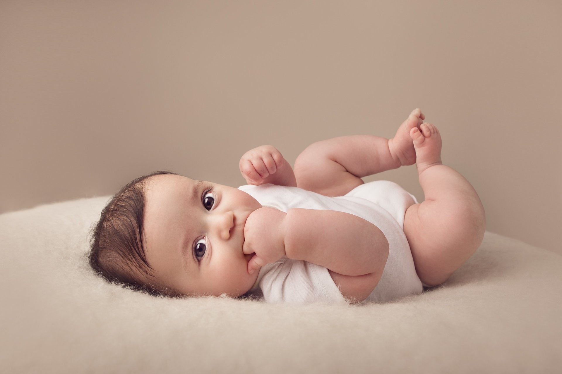 grayscale photo of baby lying on bed