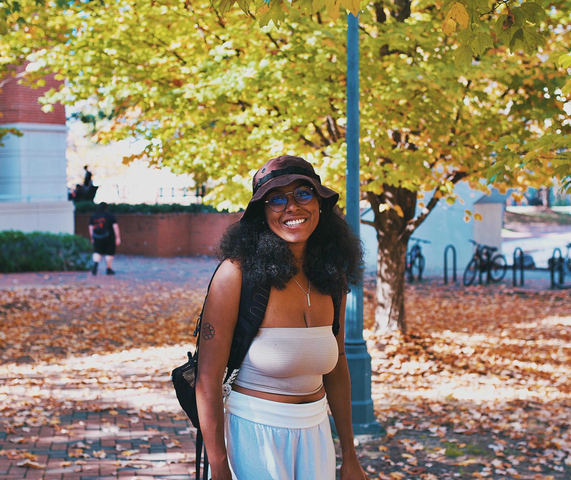 Young college black woman smiling underneath autumn trees while birdwatching.