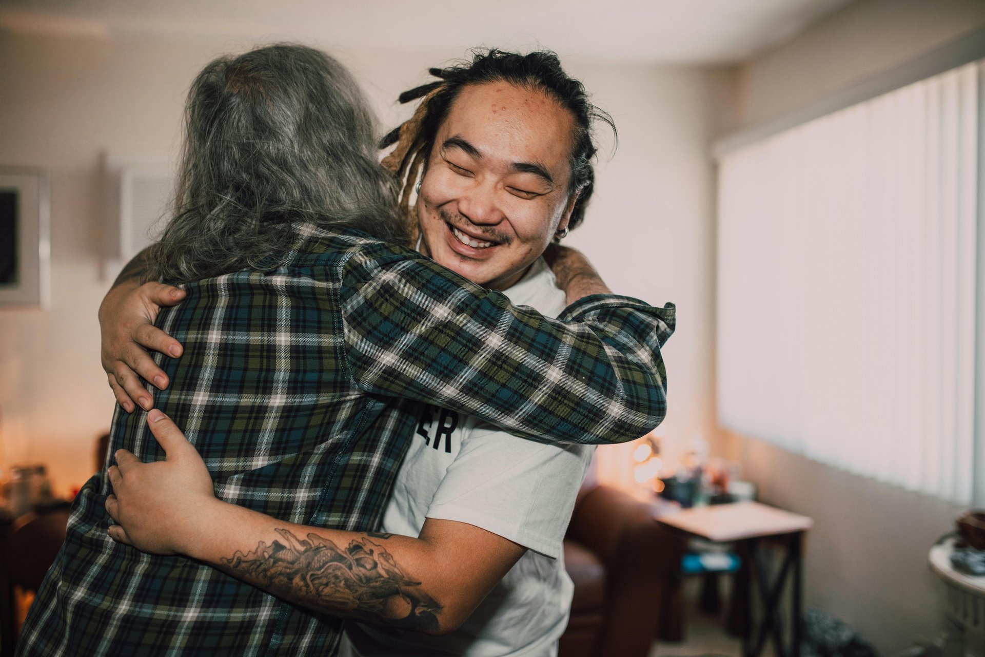 Two diverse people join together in an embrace to support refugee art initiatives.