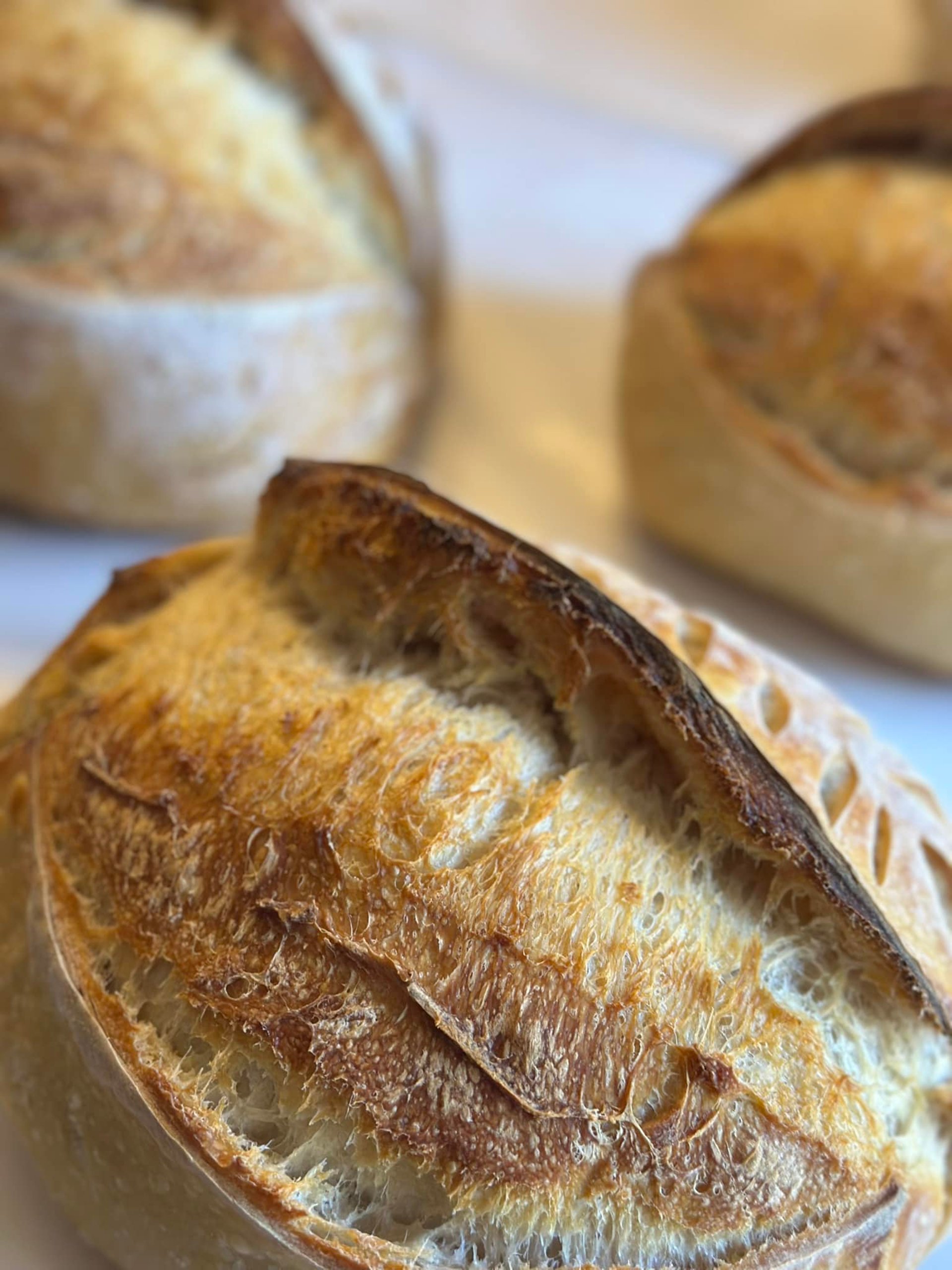 Two loaves of fresh bread sit on a cutting board.