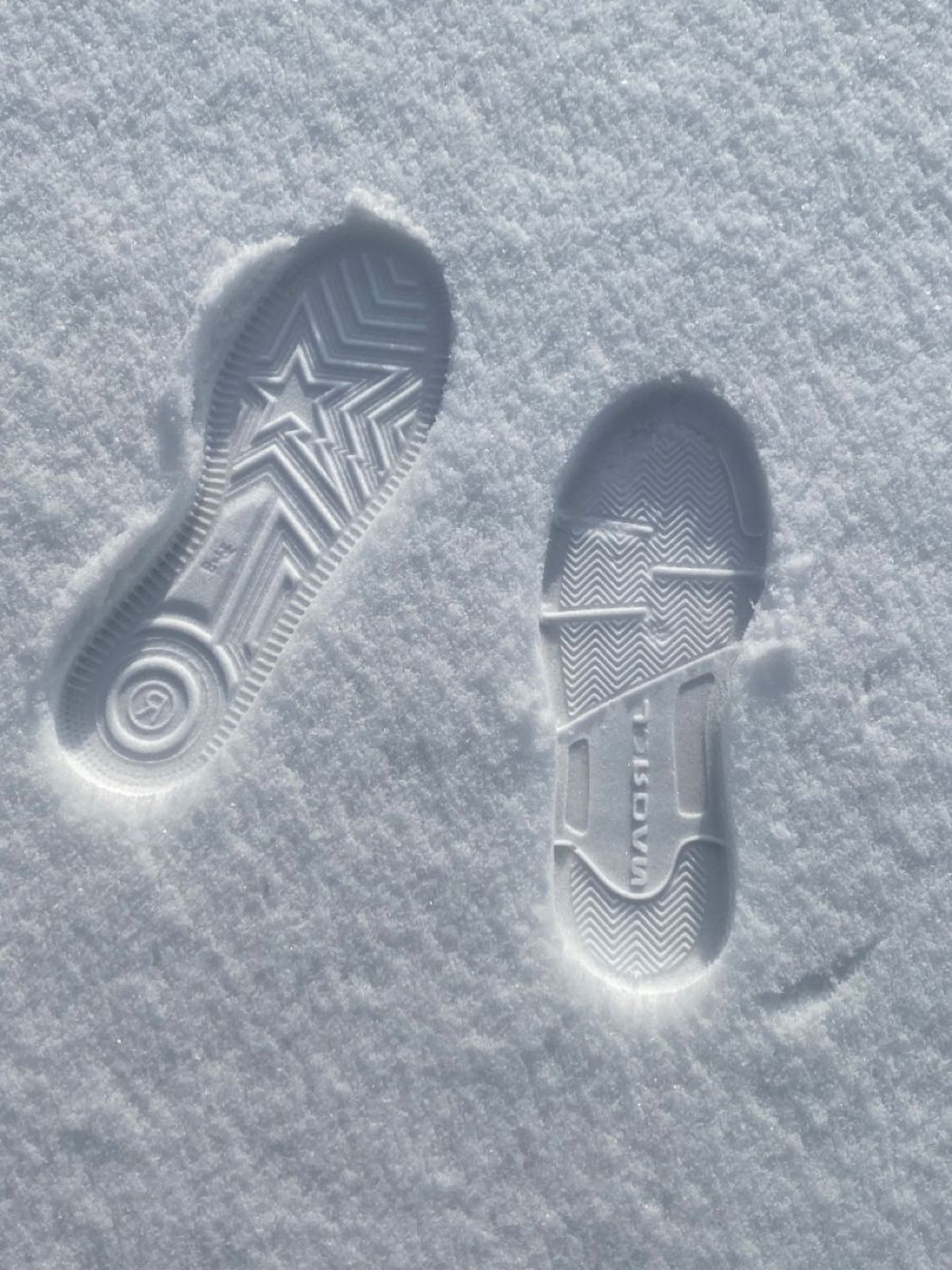 a snow covered sidewalk with footprints in the snow