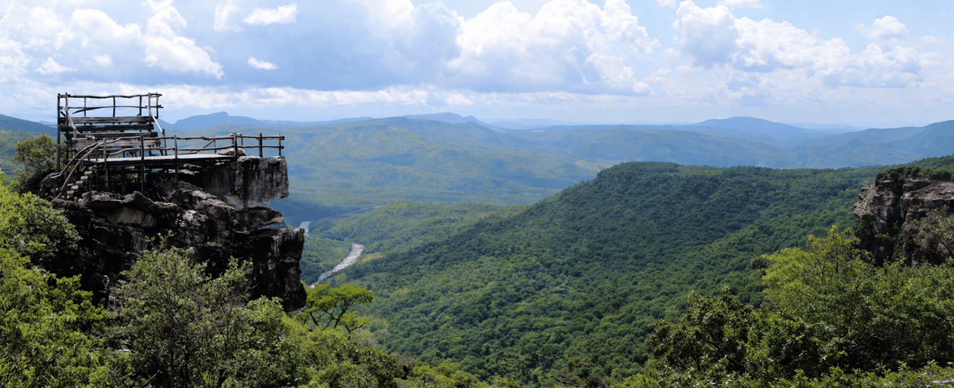 Wooden viewing platform on a rocky cliff overlooking valley.
