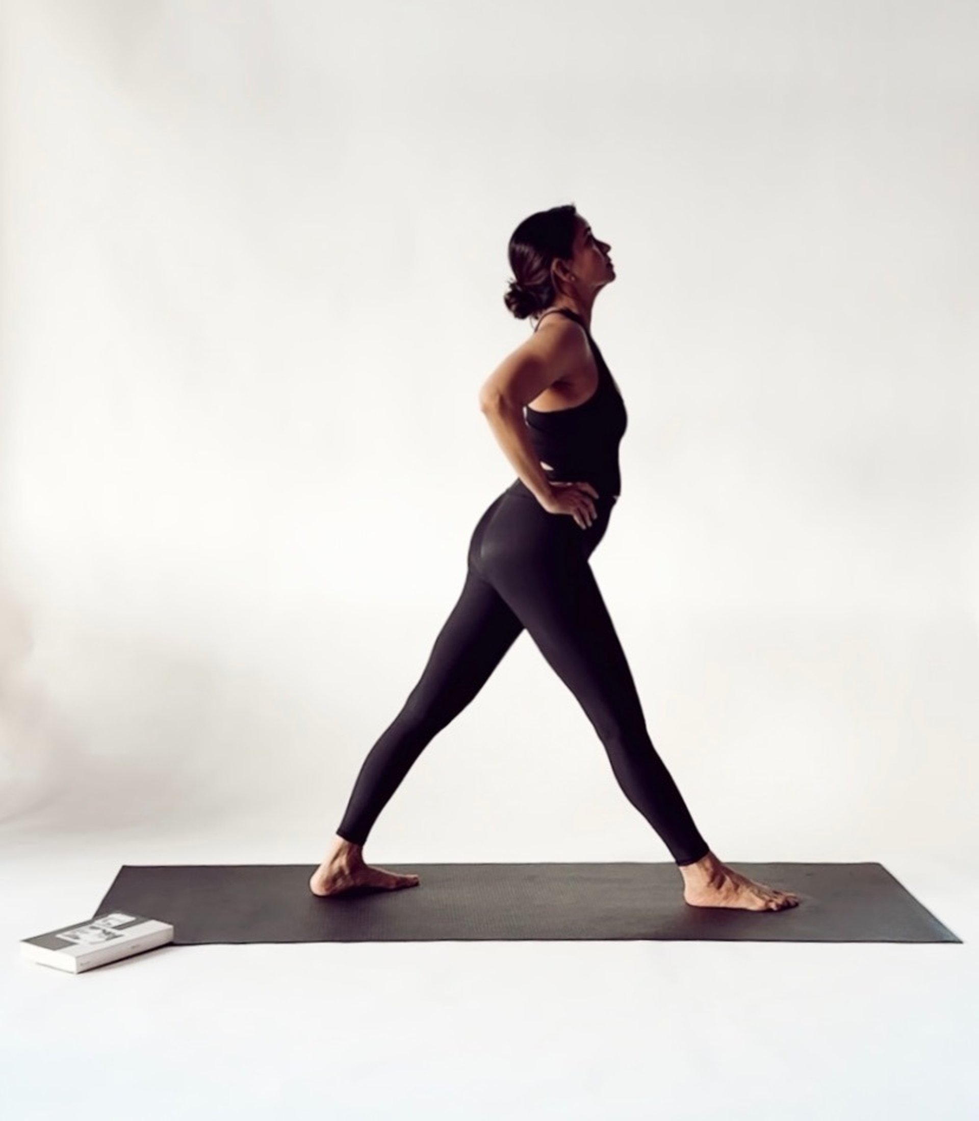 woman doing yoga on rock platform next to body of water