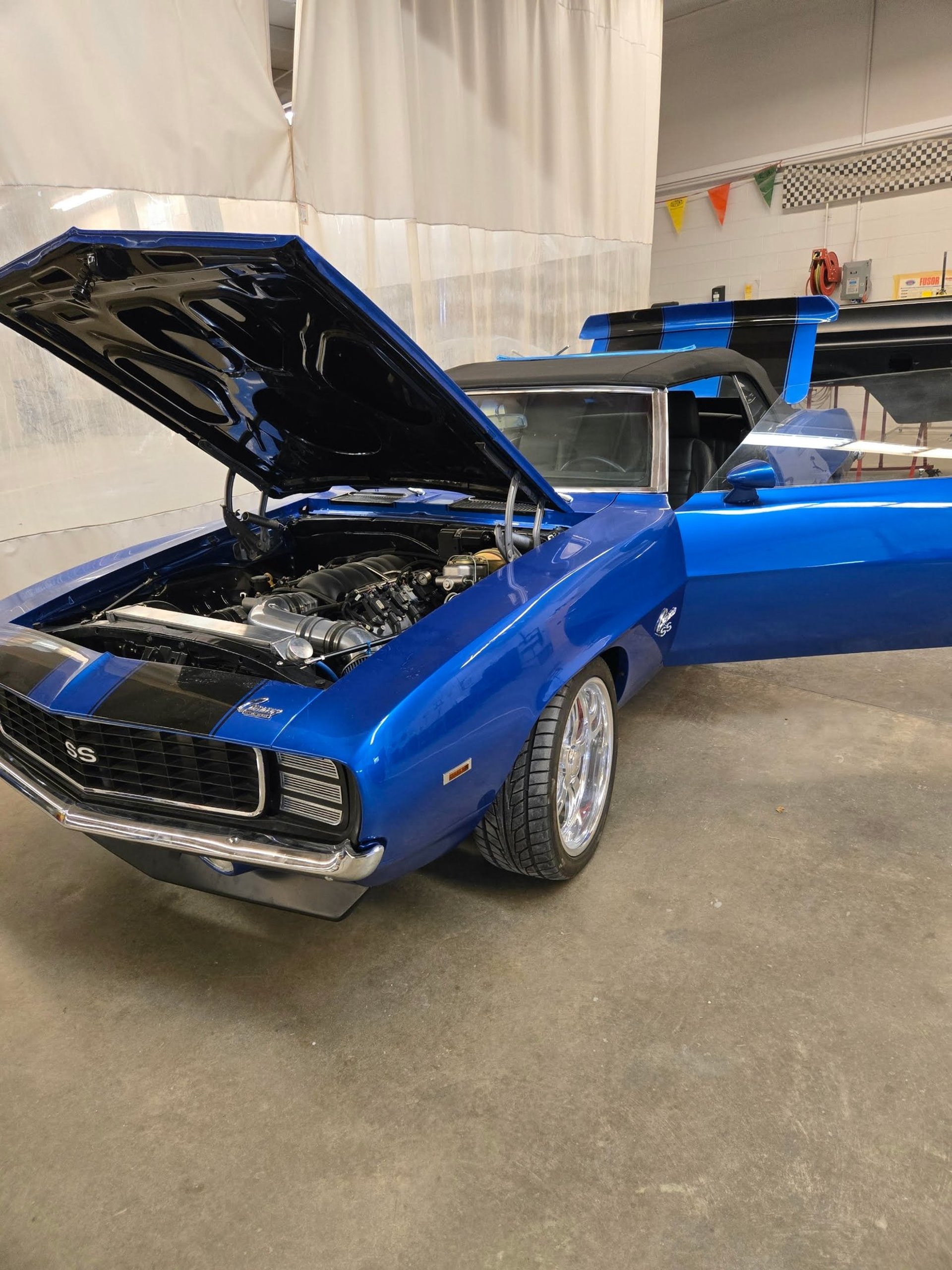 Blue classic classic muscle car with hood open inside a garage