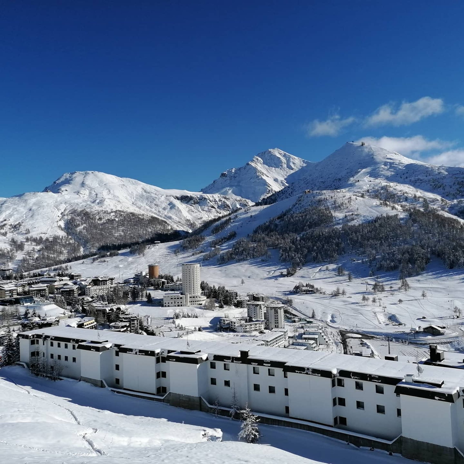 Vista su Sestriere: le due torri, le piste da sci e il monte Sises innevato.