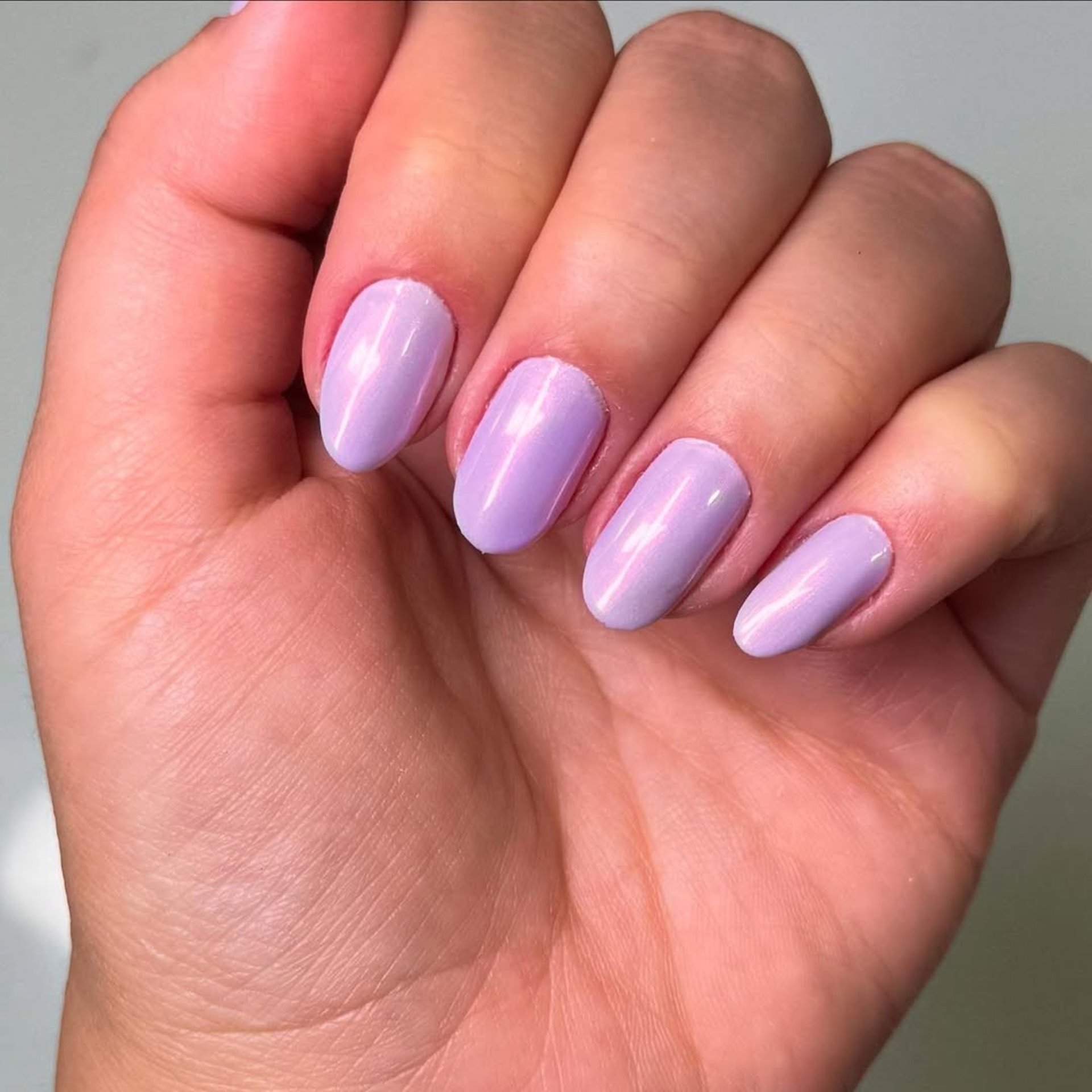 Unhas ovais com esmalte lilás perolado de efeito acetinado, ressaltando a delicadeza e a saúde das unhas naturais.
