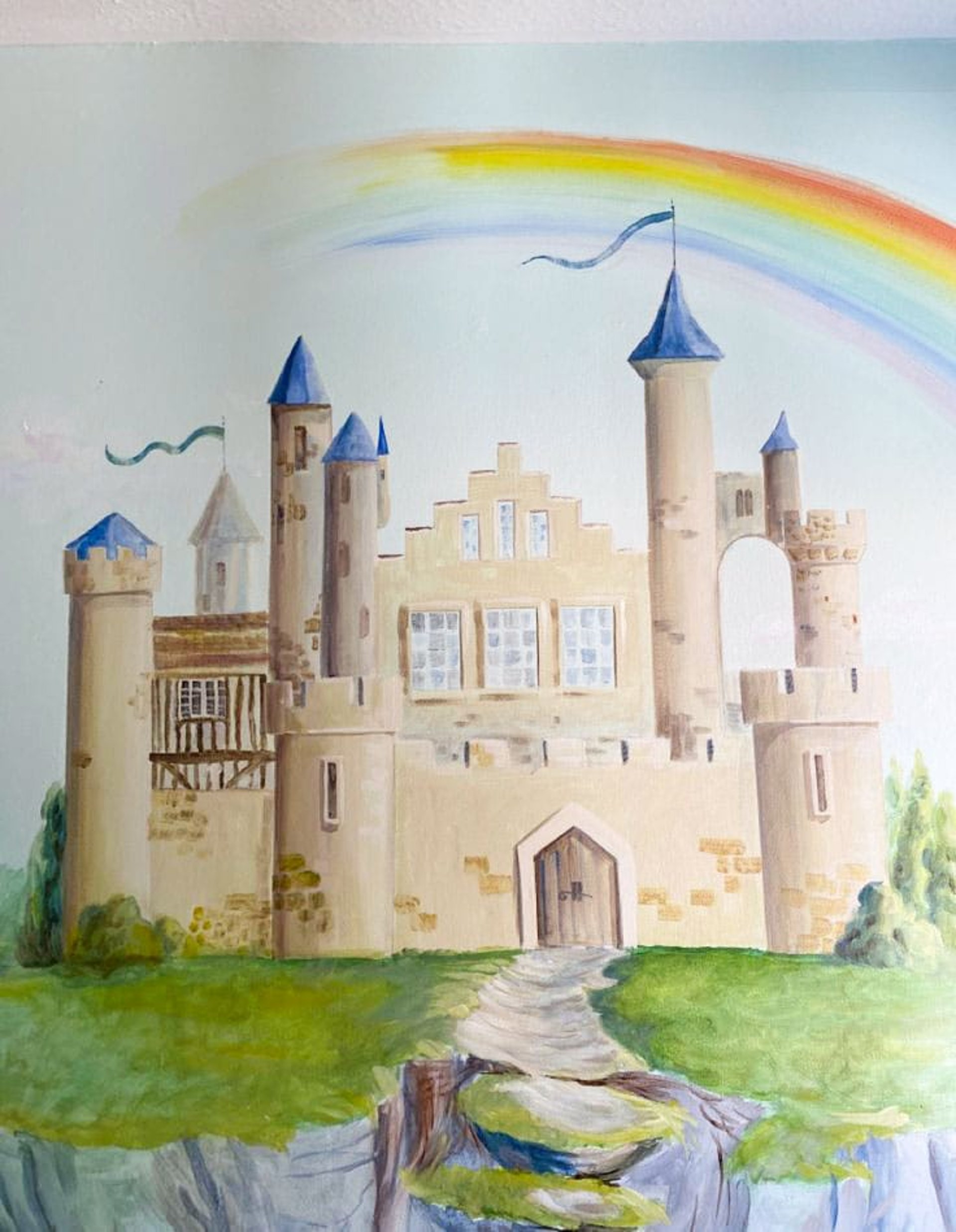 A mural of a magical castle on a floating rock in the sky, featuring blue turrets, banners, crystals and a rainbow