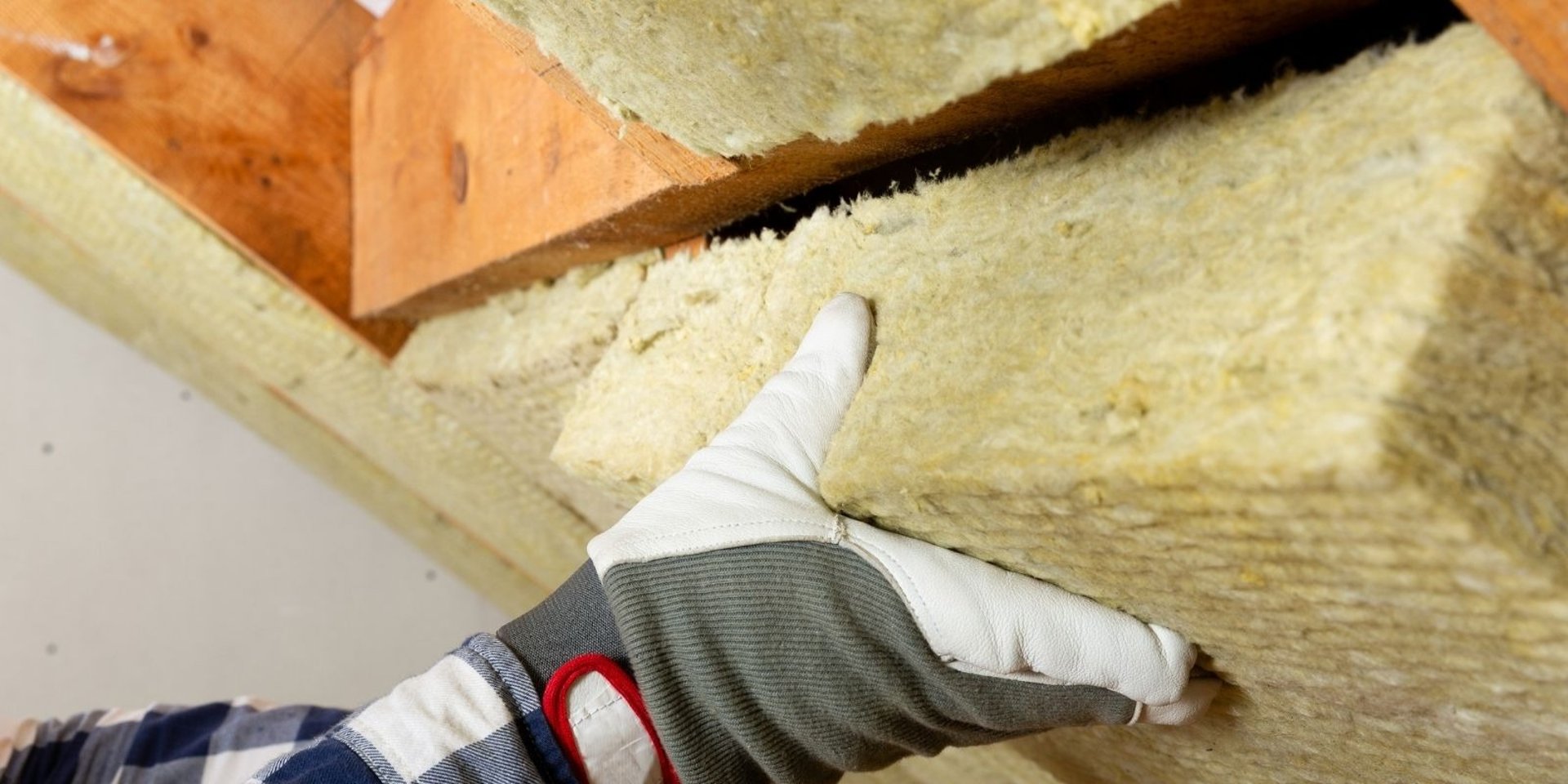 Artisan posant de la laine minérale pour l’isolation thermique d’une toiture à Montbéliard, afin d’améliorer le confort et ré