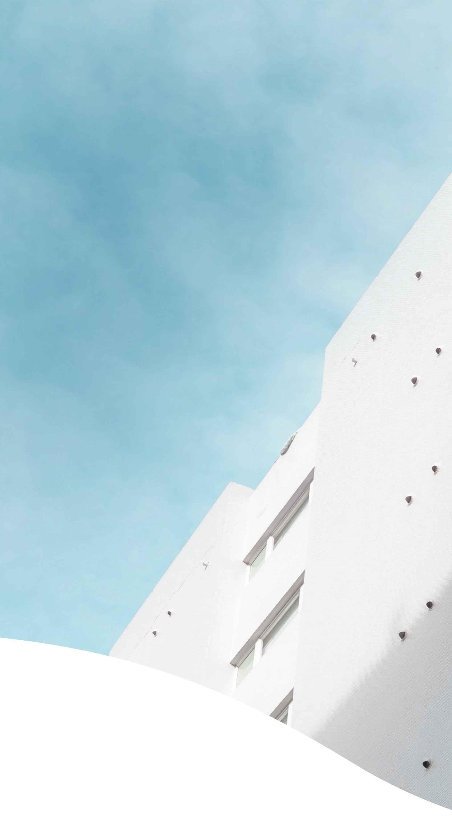 an abstract photo of a curved building with a blue sky in the background