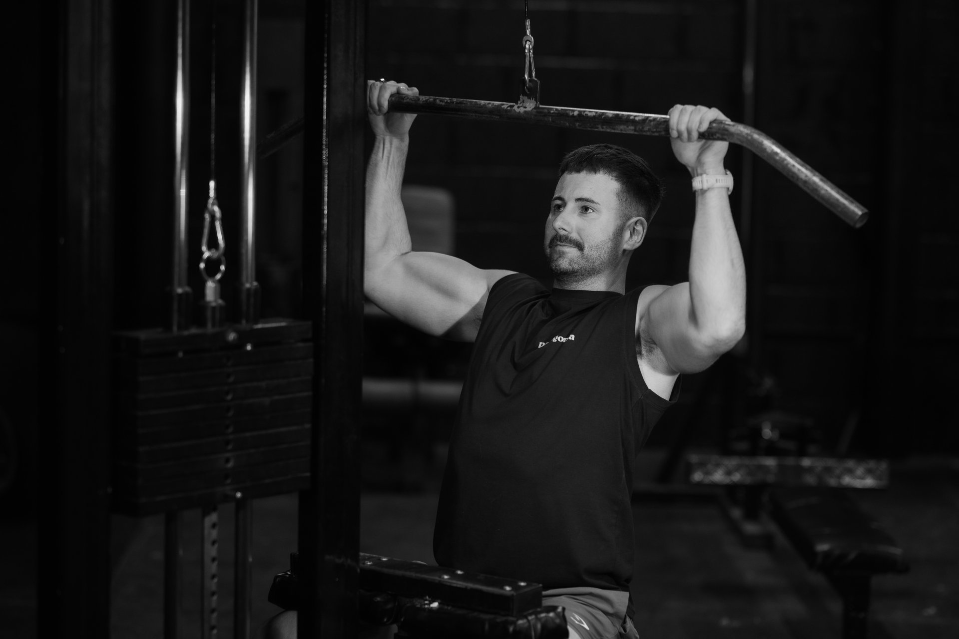 Trainer performing seated dumbbell shoulder press with 26kg weights in Leamington Spa gym, focused on strength and form