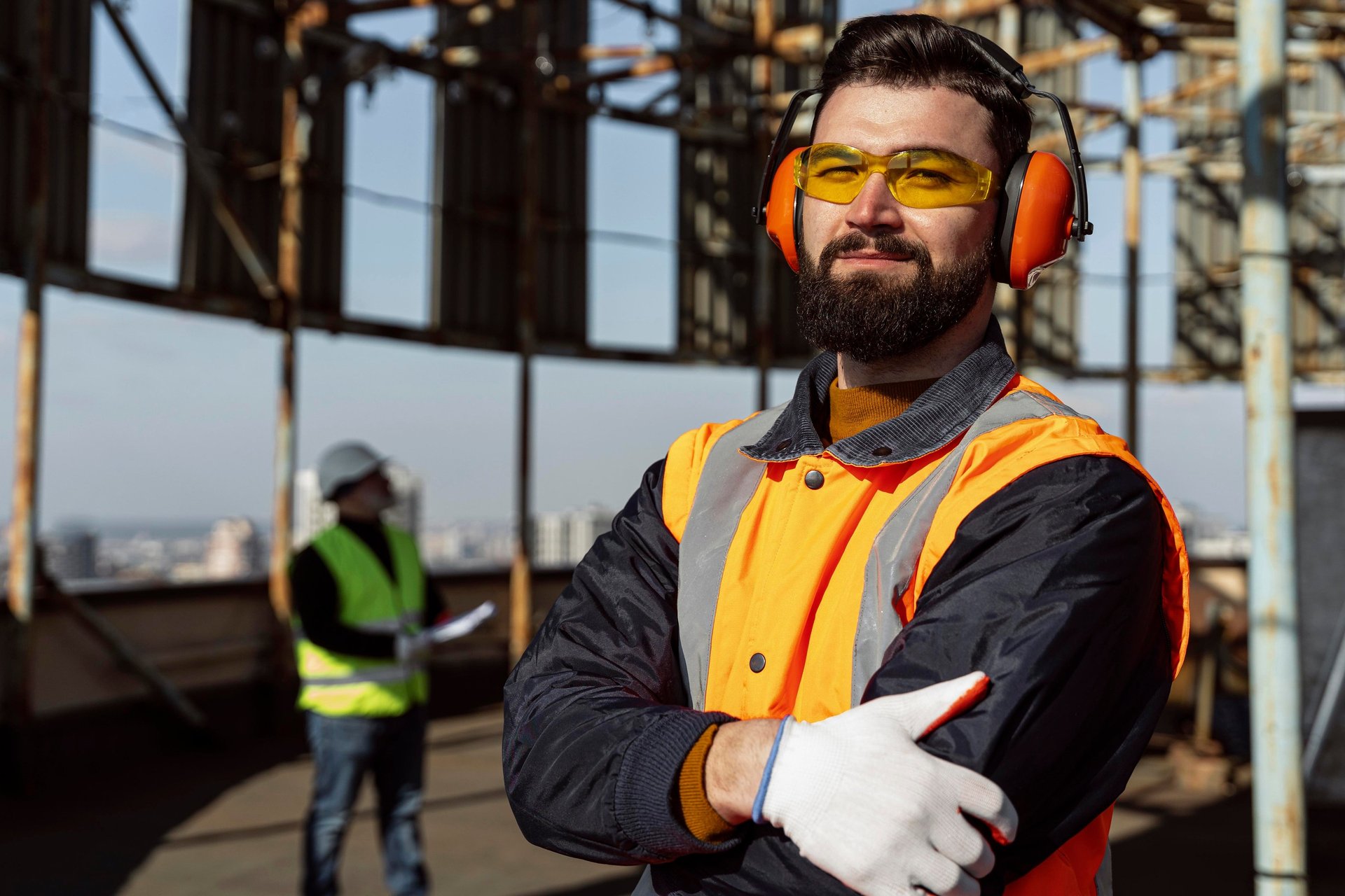 man in brown and white plaid dress shirt and yellow hard hat holding black and orange