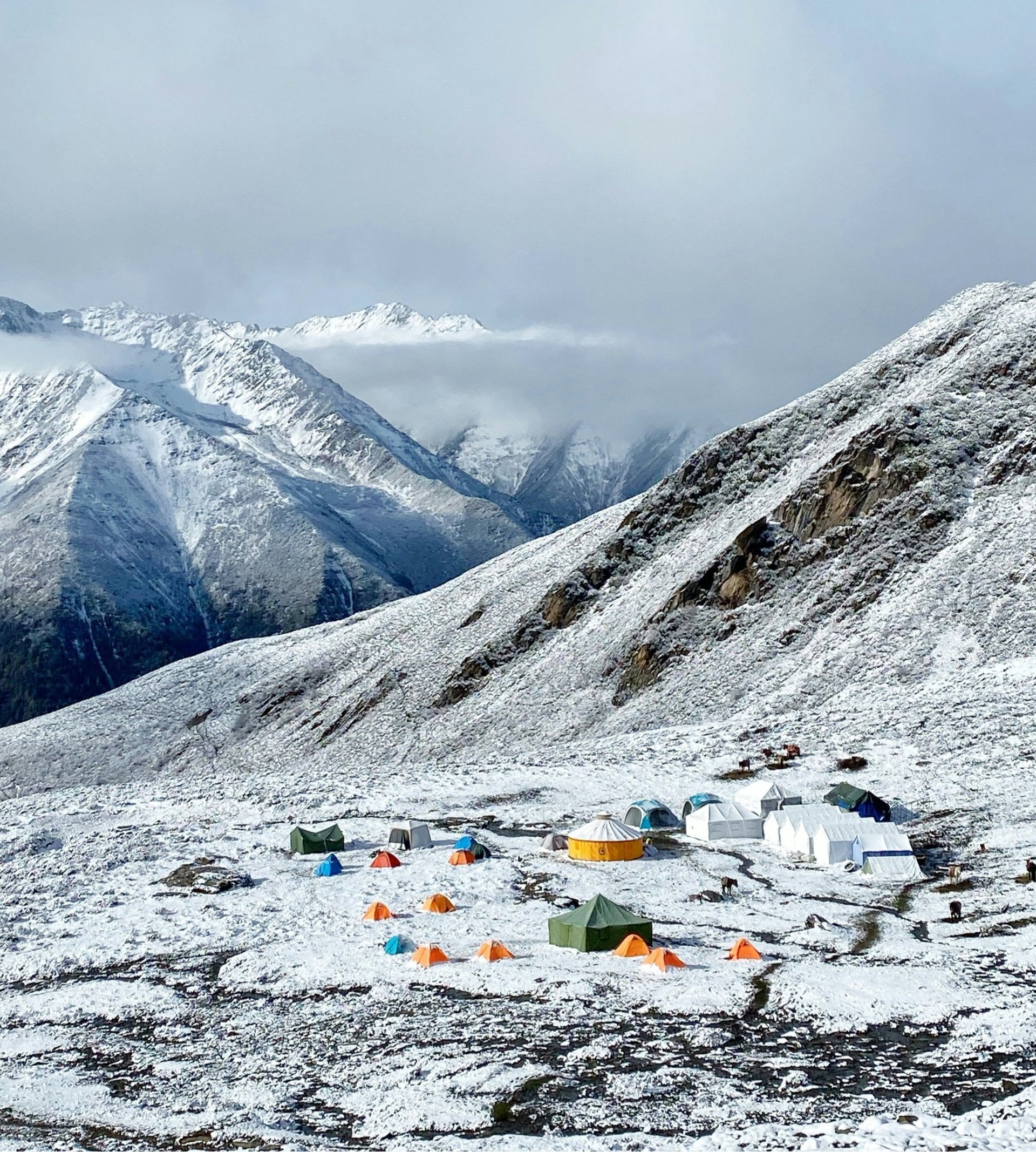 a group of tents pitched up on top of a snow covered mountain