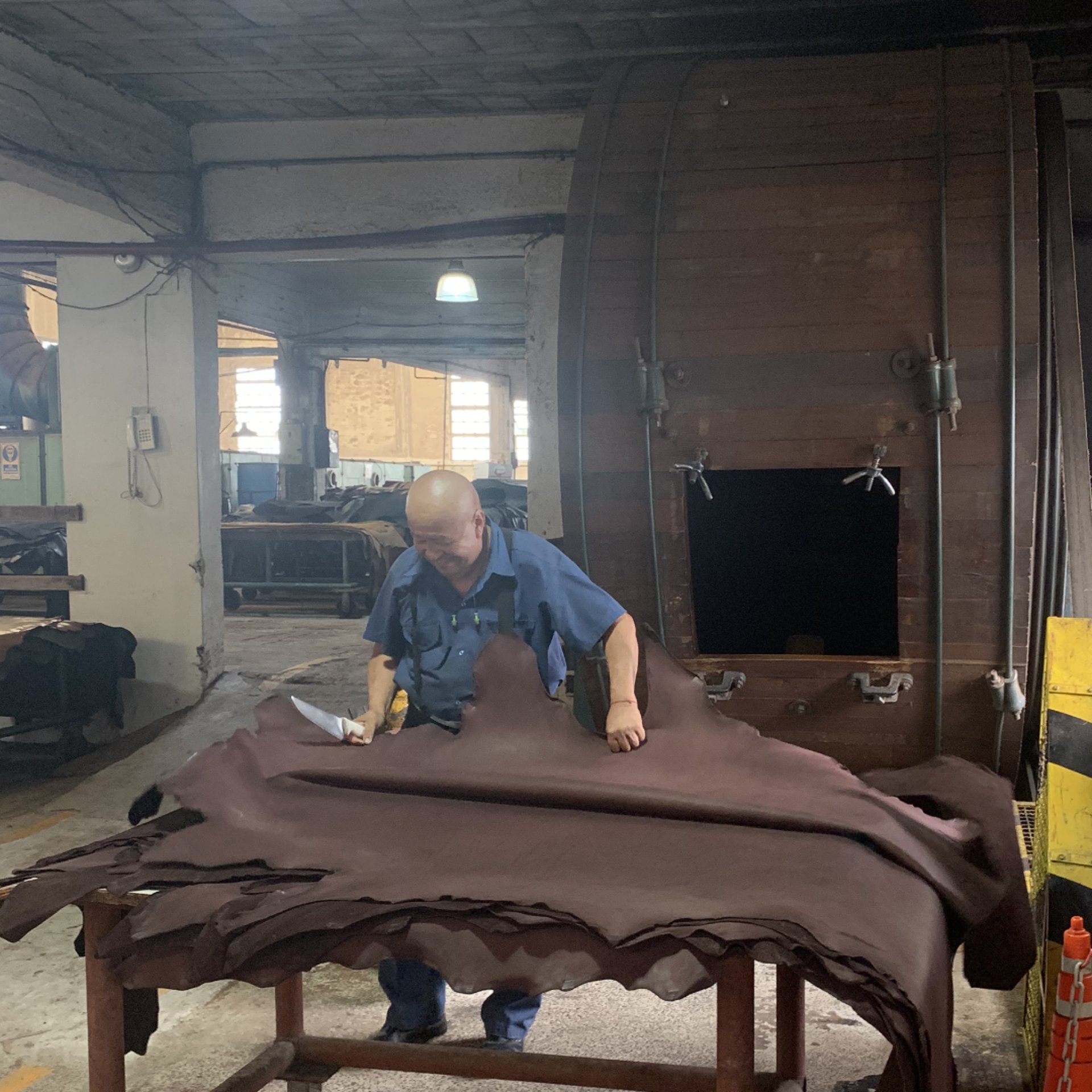 Hombre trabajando el cuero con tambor de curtido en curtiembre en pleno funcionamiento, proceso artesanal.