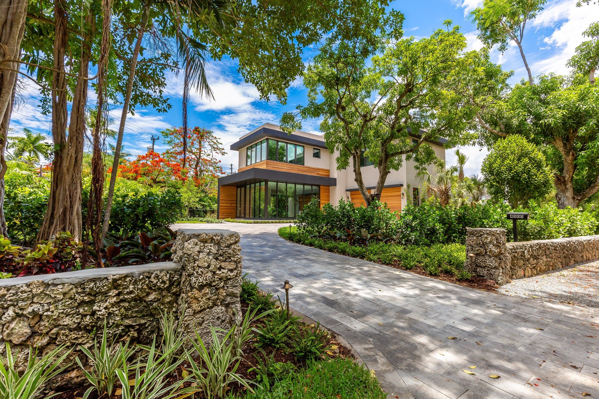 brick driveway leading to a vibrant front yard of a custom built luxury home