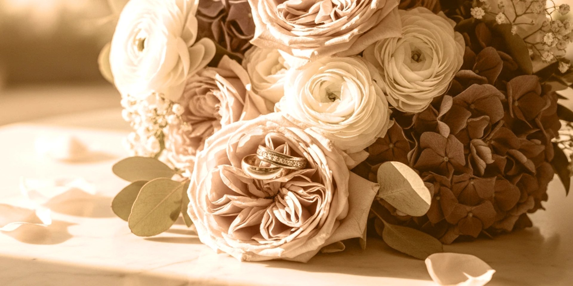 gold-colored bridal ring set on pink rose flower bouquet