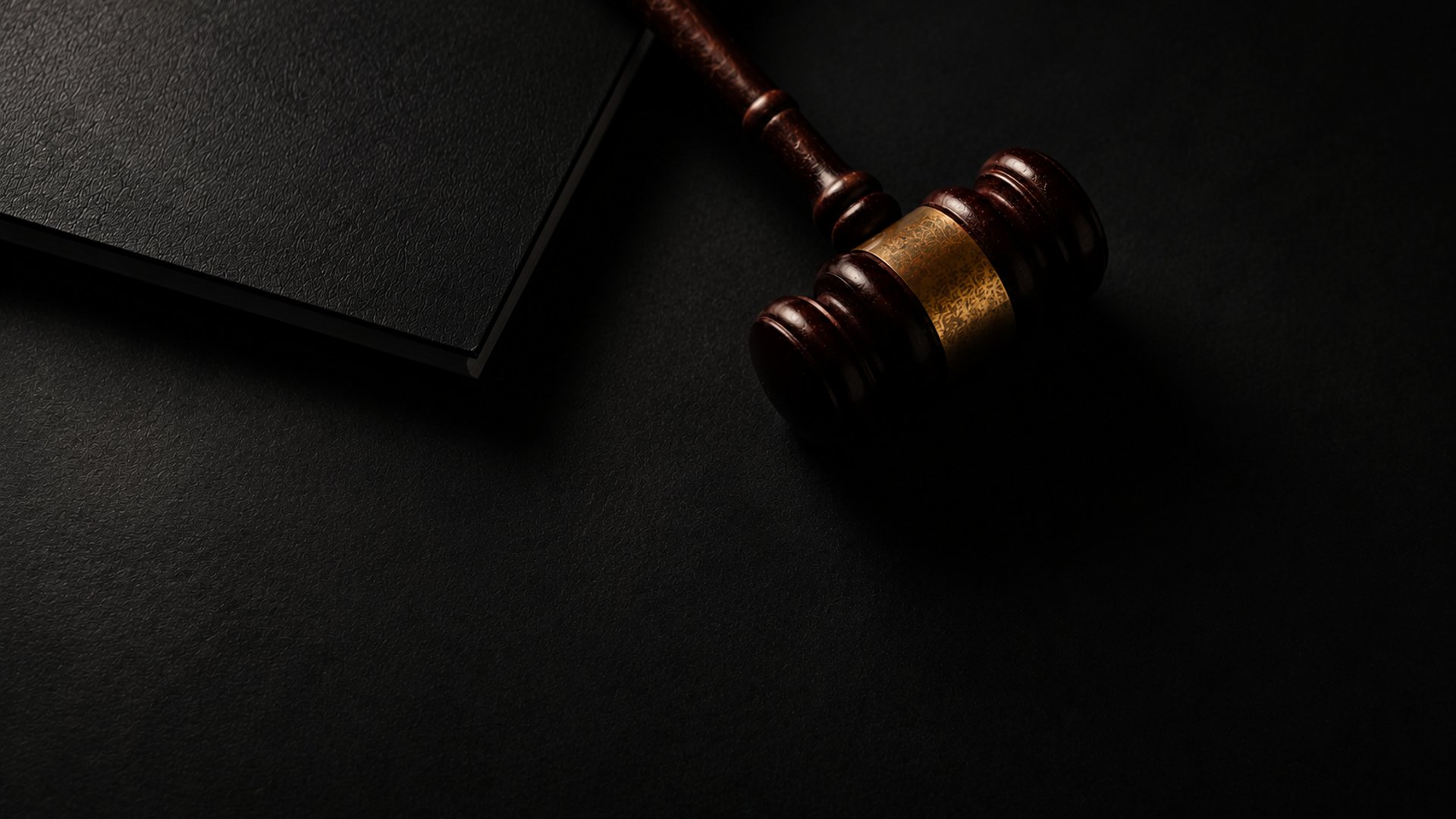 Wooden gavel resting on a dark surface next to book