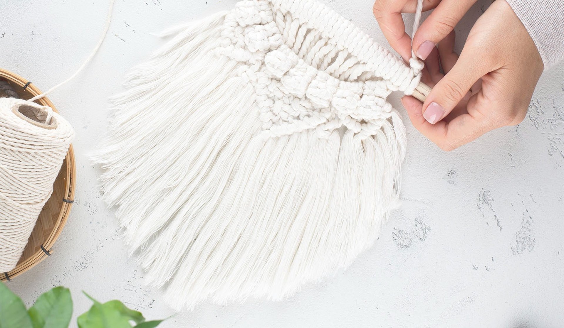 Manos tejiendo macramé con cordón de algodón blanco